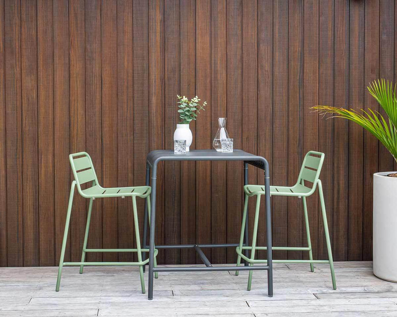 Green Frankie bar stools with slatted seats and backs, paired with the charcoal Atticus bar leaner in a contemporary outdoor setting.
