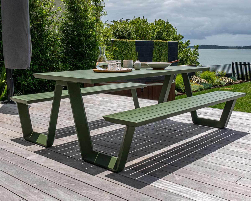 Tahoe outdoor picnic table in forest green with slatted table top and bench seats, styled on a timber deck overlooking the water.