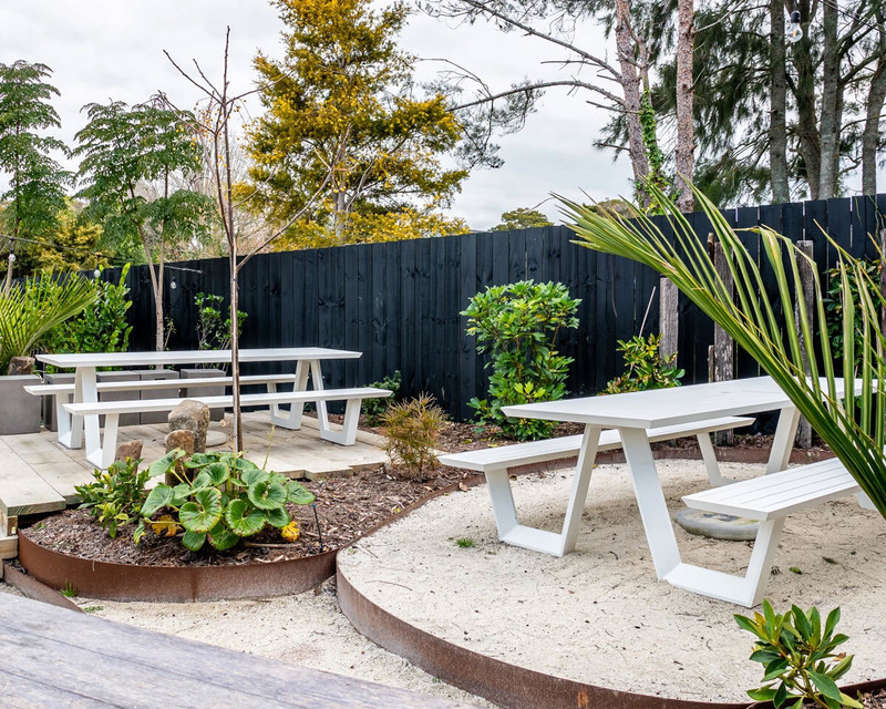 Green Frankie bar stools with slatted seats and backs, paired with the charcoal Atticus bar leaner in a contemporary outdoor setting.