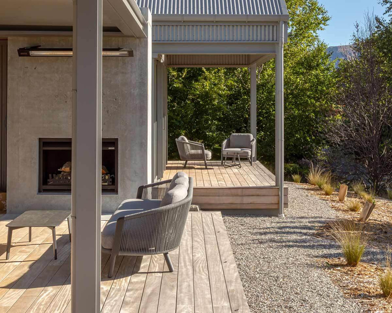 Arc outdoor sofa and armchairs with grey cushions and rope detailing arranged on a timber deck.