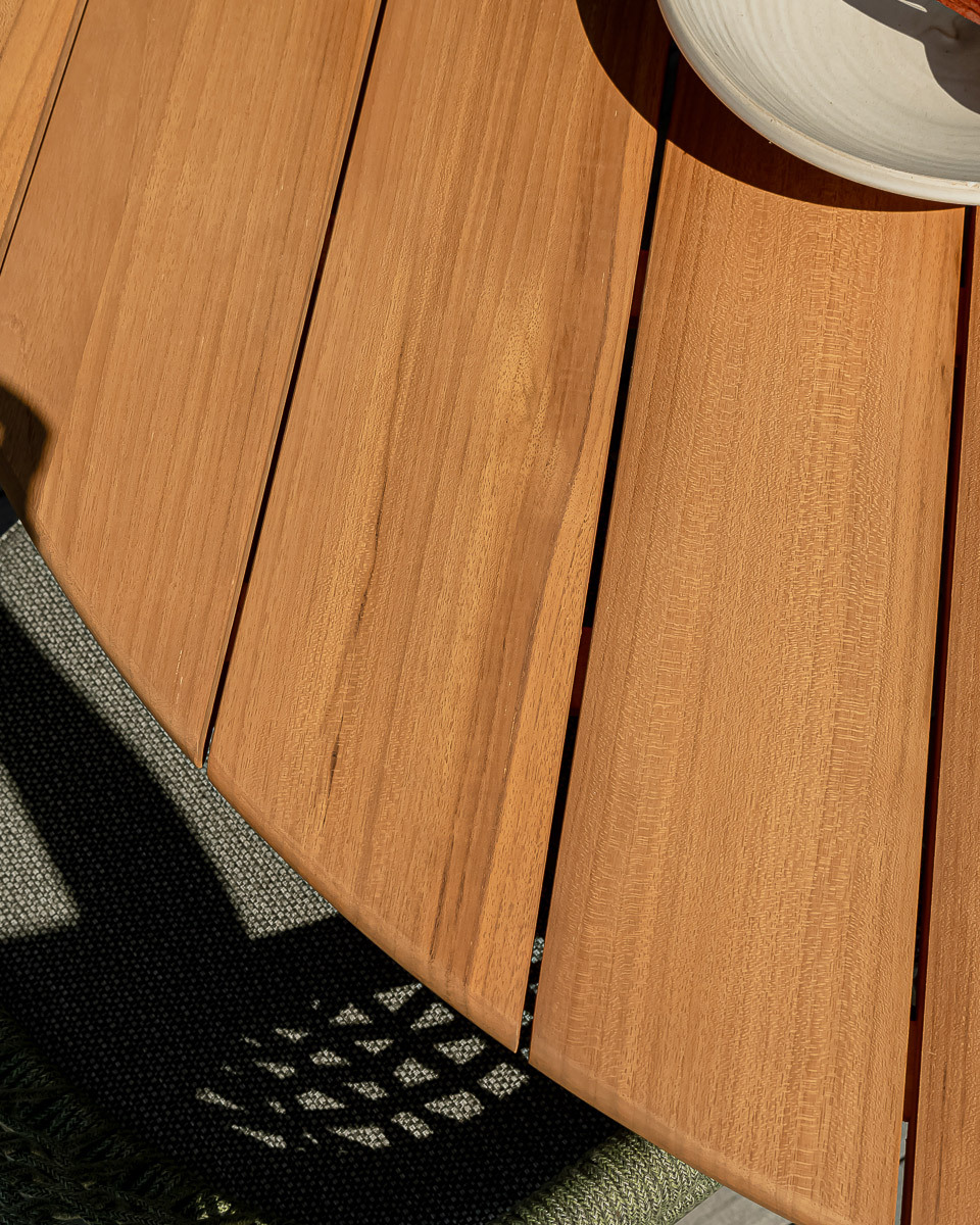 Close up of slatted teak timber table with curved edge