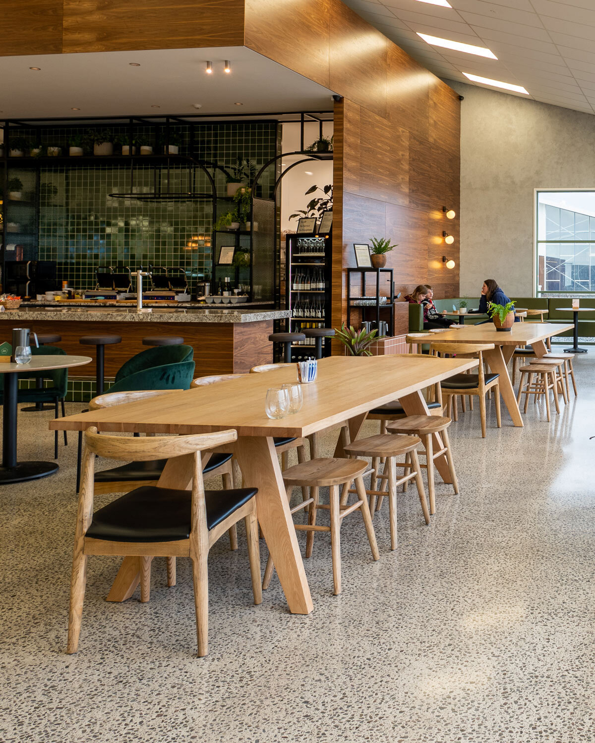 Stockholm dining table in natural oak paired with low stools and elbow dining chairs at an airport cafe.