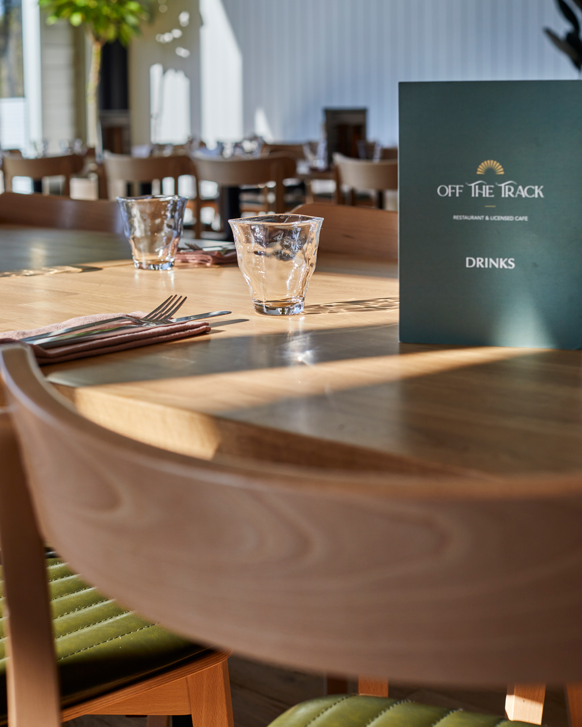 Close-up of timber restaurant table settings and dining chairs at Off The Track Restaurant & Licensed Café.