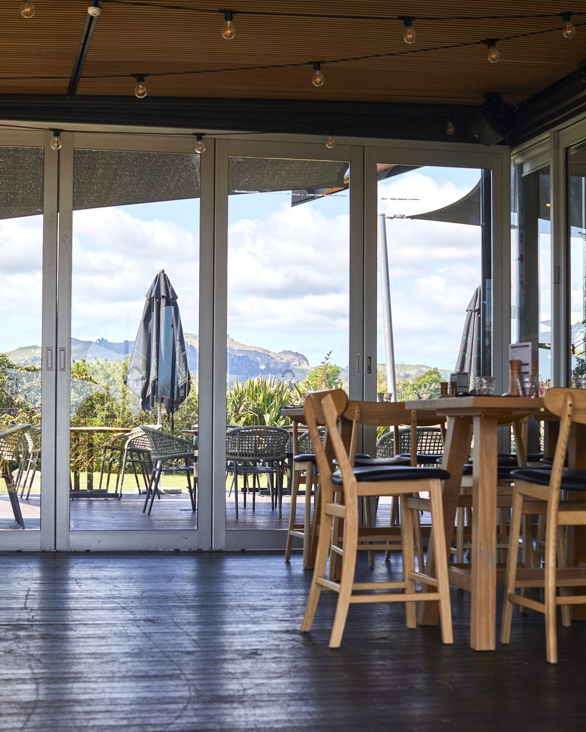 Restaurant dining area with indoor-outdoor flow, timber furniture and views across the outdoor terrace.