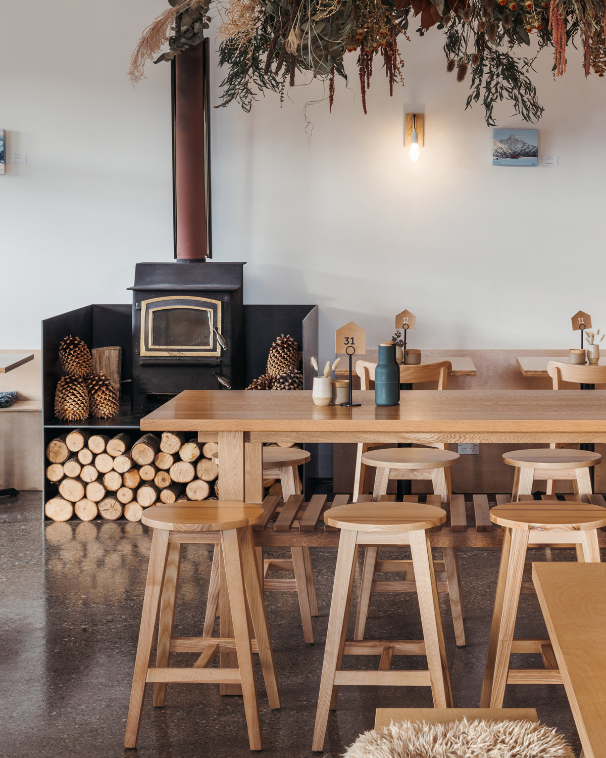 Albert timber bar stools styled within a warm and natural caf&eacute; interior in Wanaka with solid timber tables and soft neutral finishes.