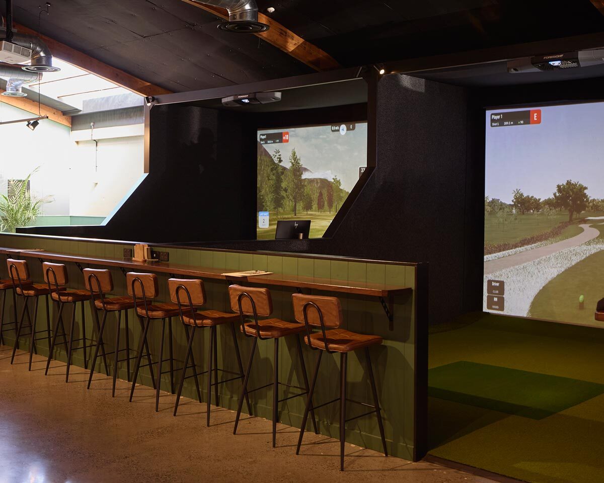 Walter bar stools in Chestnut providing comfortable seating beside the golf simulators at The 19th