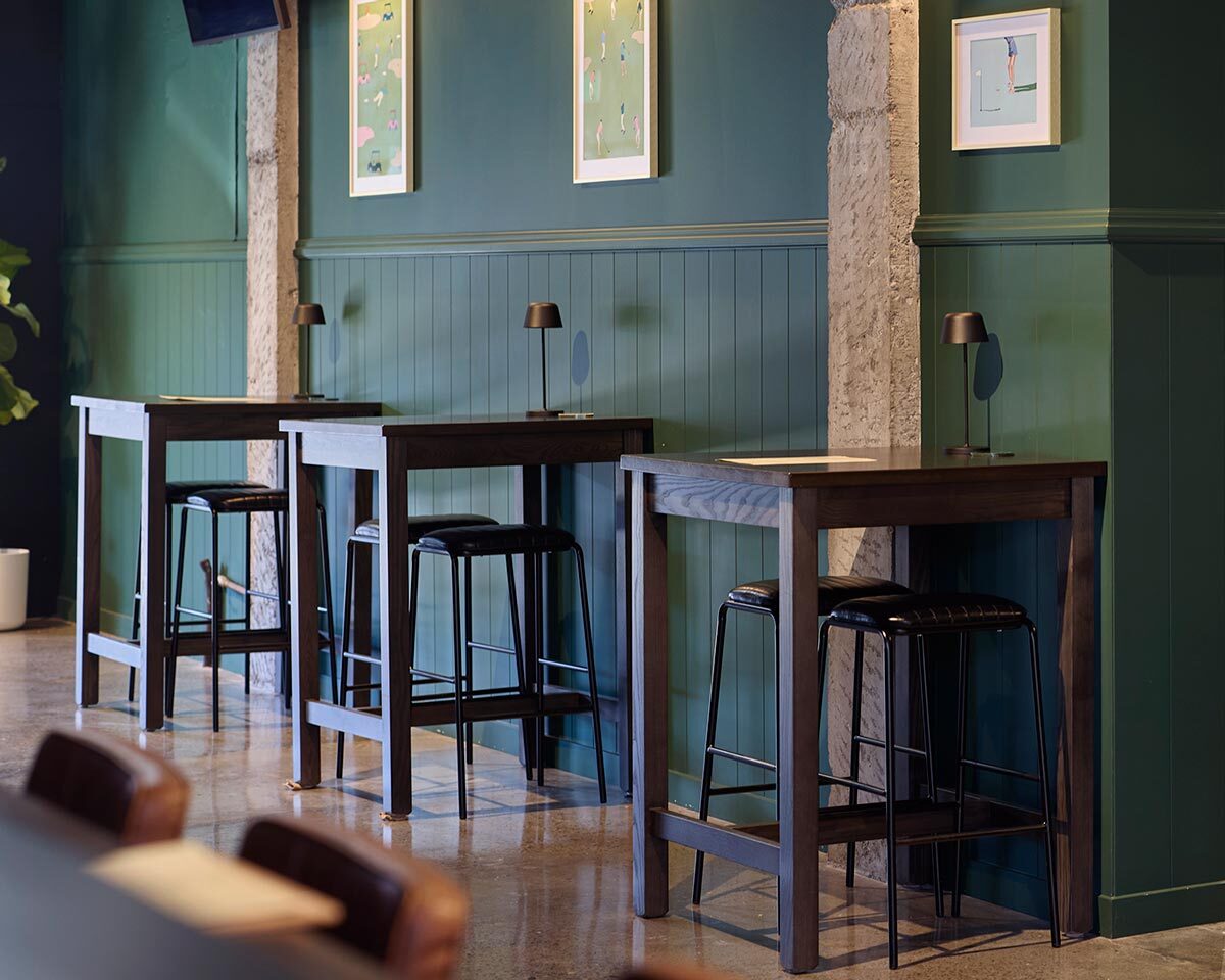 Bruce black vinyl bar stools paired with timber bar leaners at The 19th