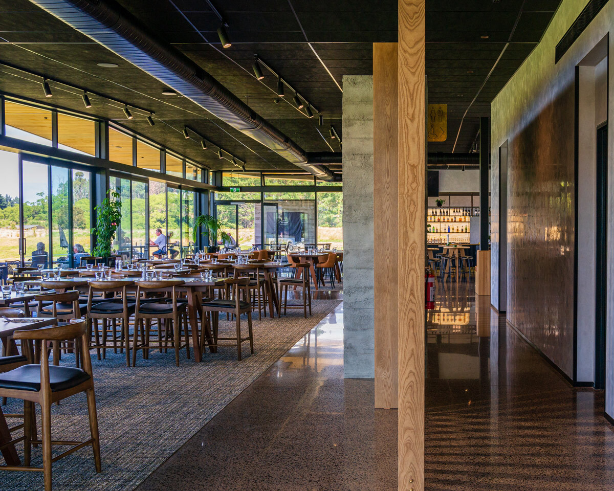 Interior view of Tieke Golf Estate clubhouse showing restaurant furniture, lounge seating, and floor-to-ceiling windows overlooking the golf course.