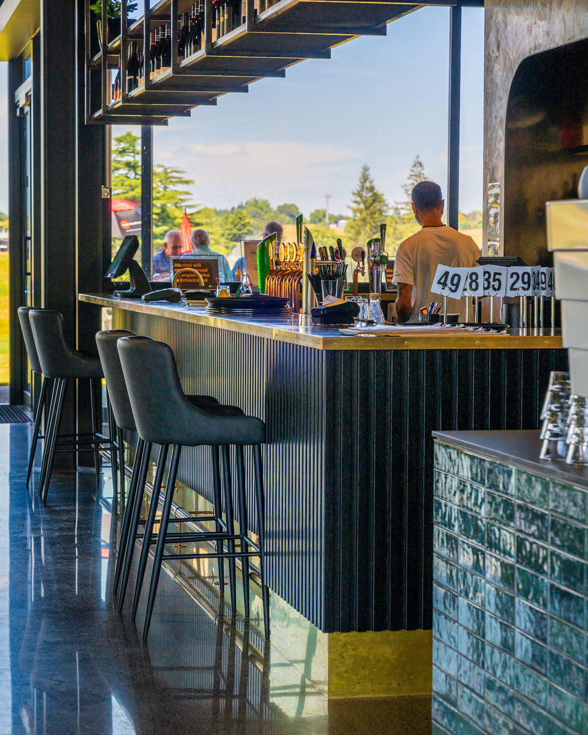 Bar seating area at Tieke Golf Estate featuring upholstered bar stools and views across the golf course.