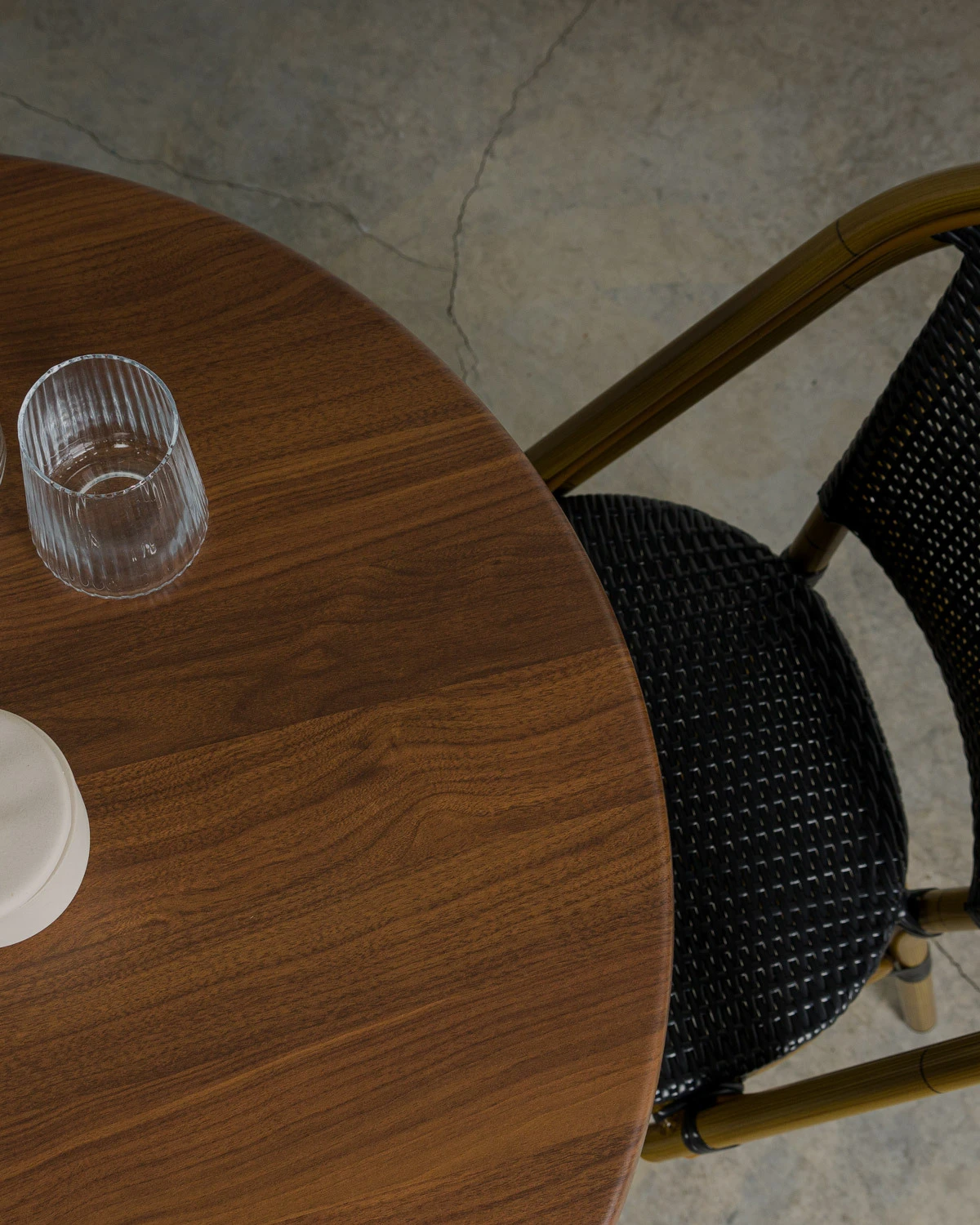birds eye view of dark oak grained table top paired with a black woven Chloe chair