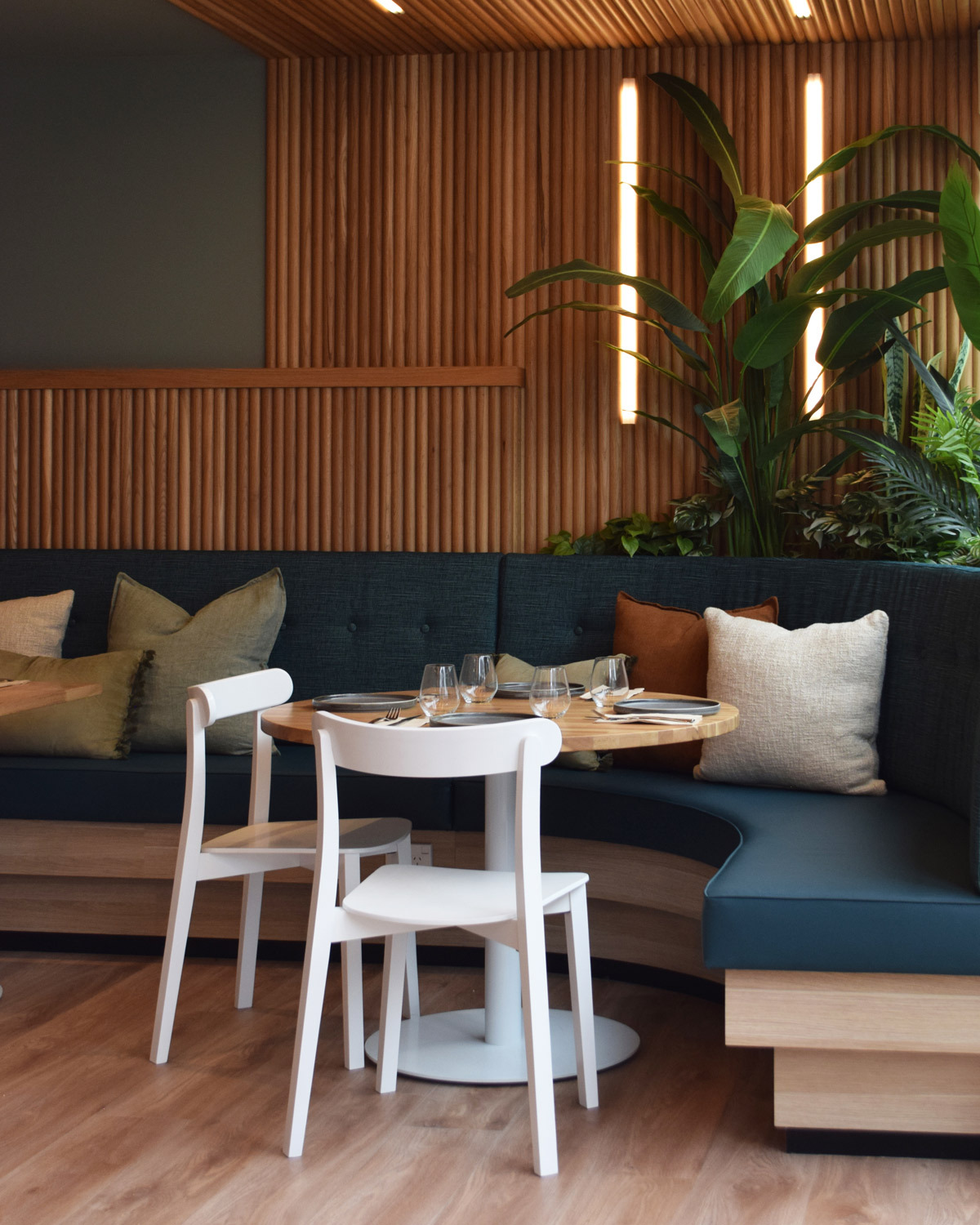 White Icho dining chair paired with round base & natural oak table top in a restaurant setting.