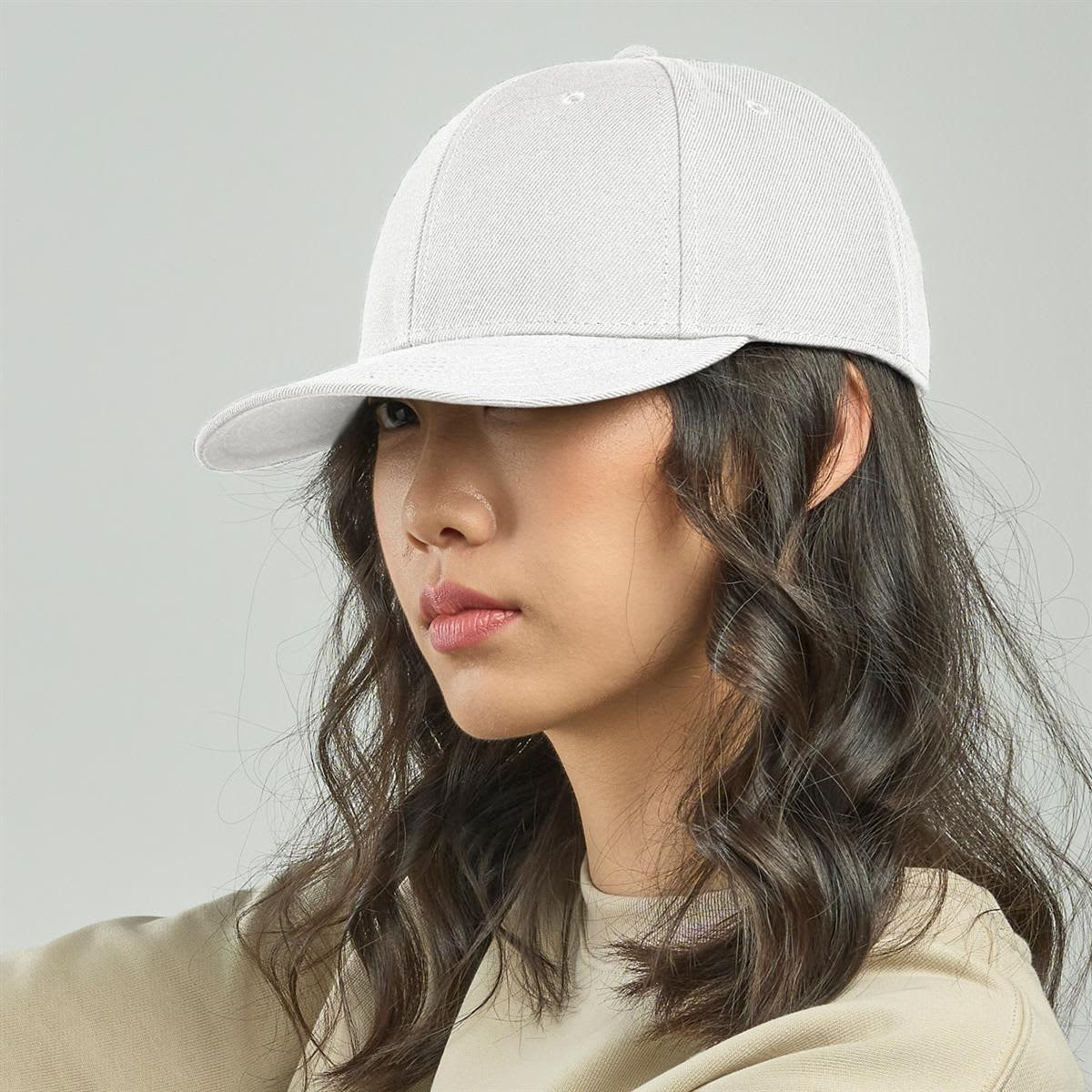 A white cap with a curved brim, featuring an adjustable strap and a logo. The model has wavy hair.