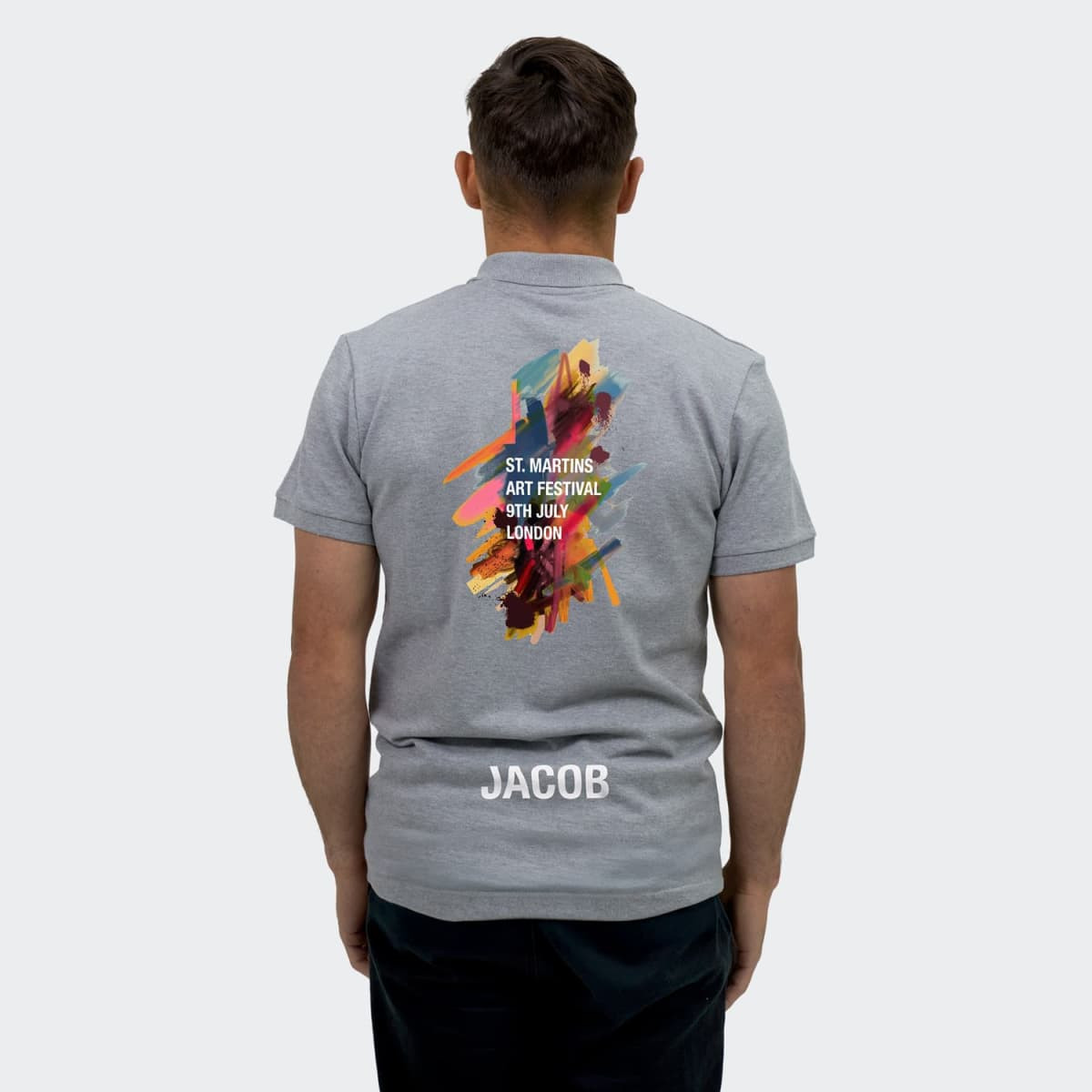 A grey men's polo shirt featuring a colourful design on the back and a logo at the bottom.