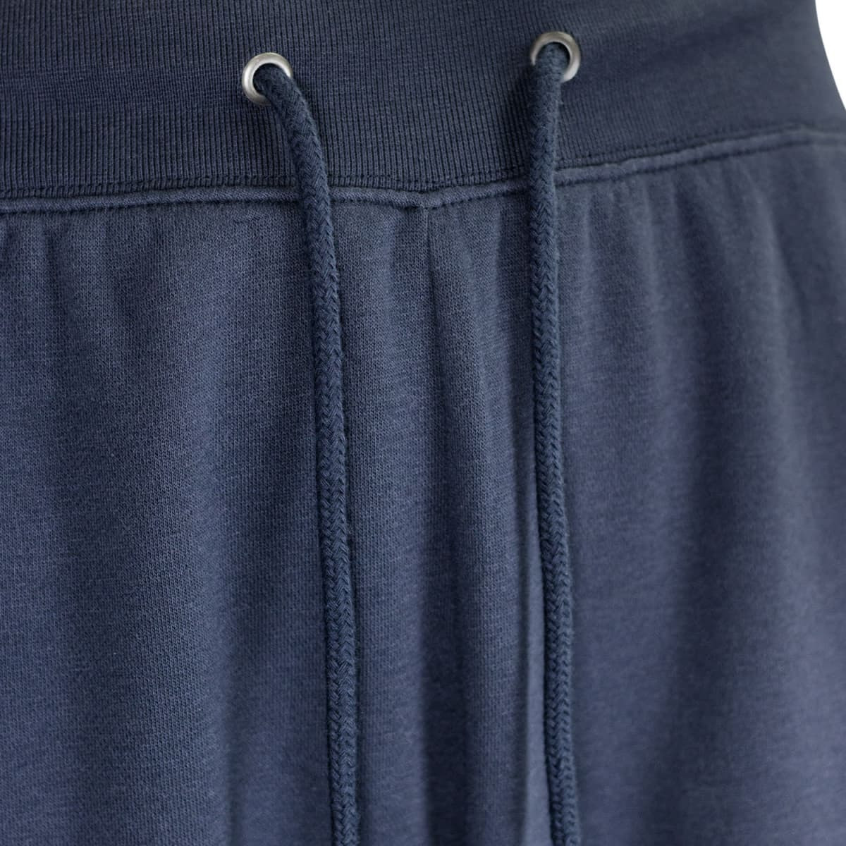 Navy blue unisex sweatpants featuring an elastic waistband with drawstrings and metal eyelets. Includes a logo.