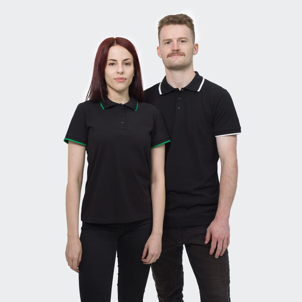 A black women's polo shirt with green trim, alongside a black men's polo shirt with white trim. Both have logos.