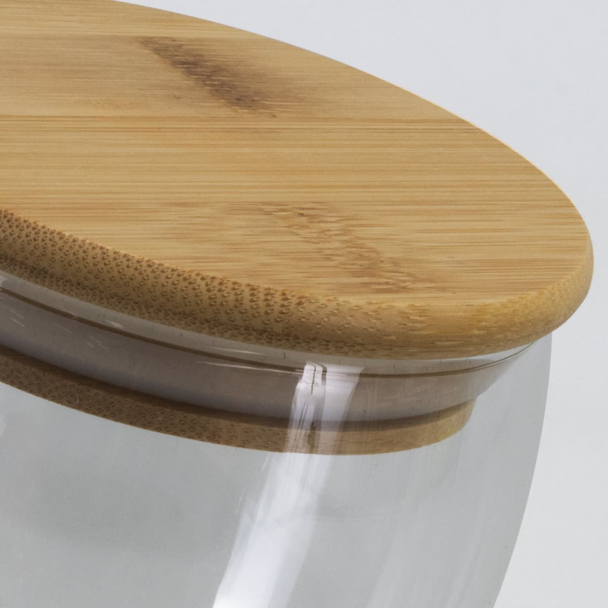 A drink bottle with a transparent glass body and a smooth bamboo lid.
