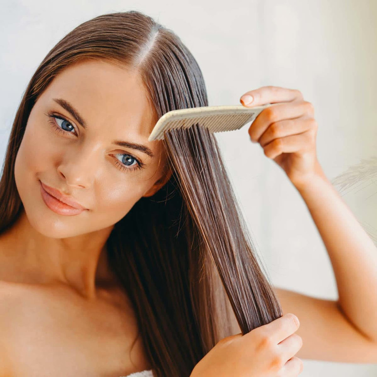 A woman is using a Lynx Wheat Fibre Comb to style her long, straight hair.