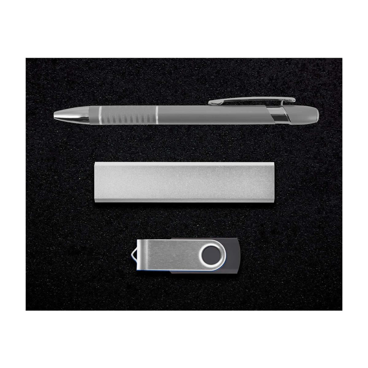A silver pen, a sleek metal bar, and a silver USB drive arranged on a black background.