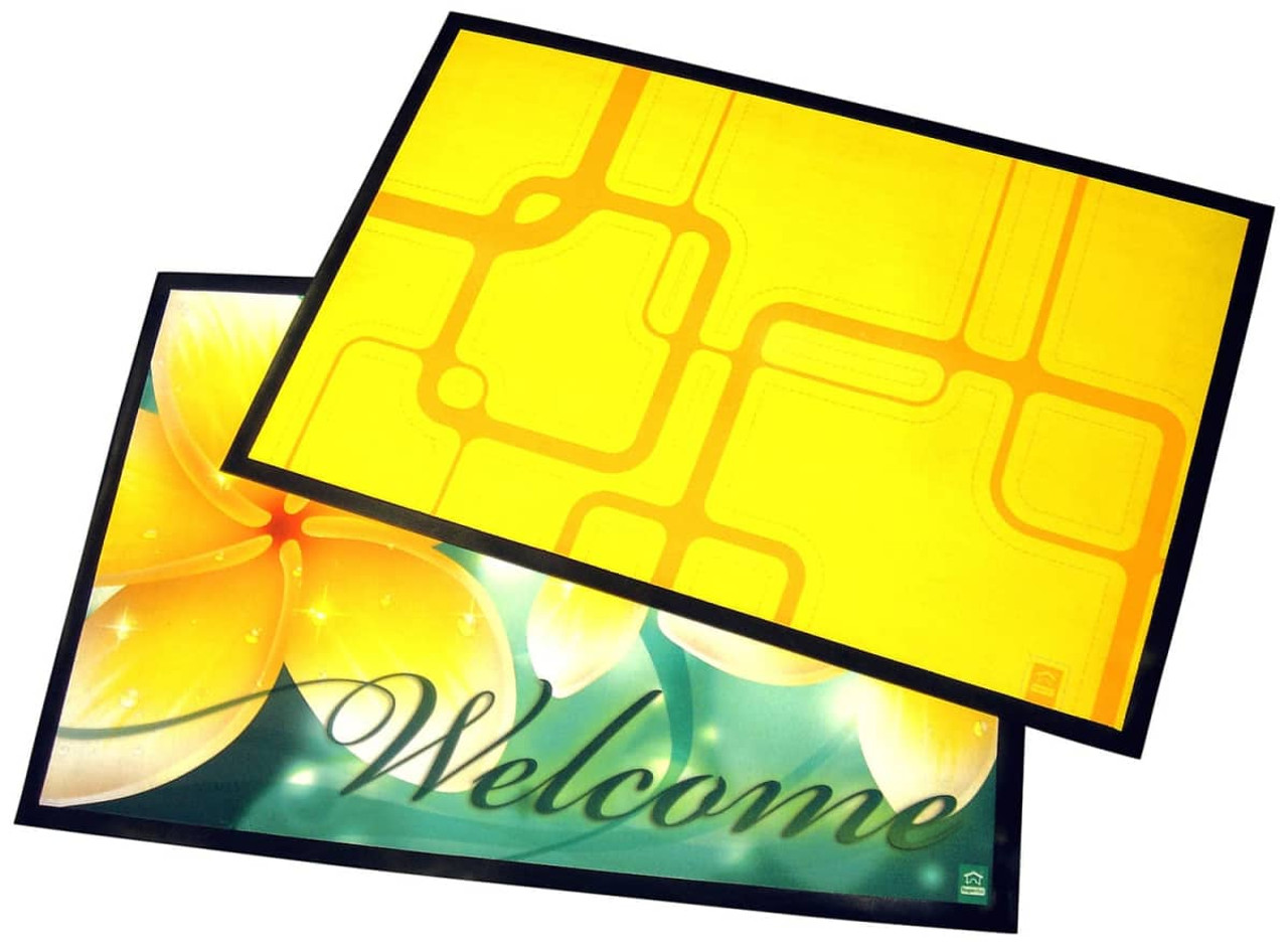 A large table mat featuring a vibrant yellow design on one side and a floral green "Welcome" design on the other.