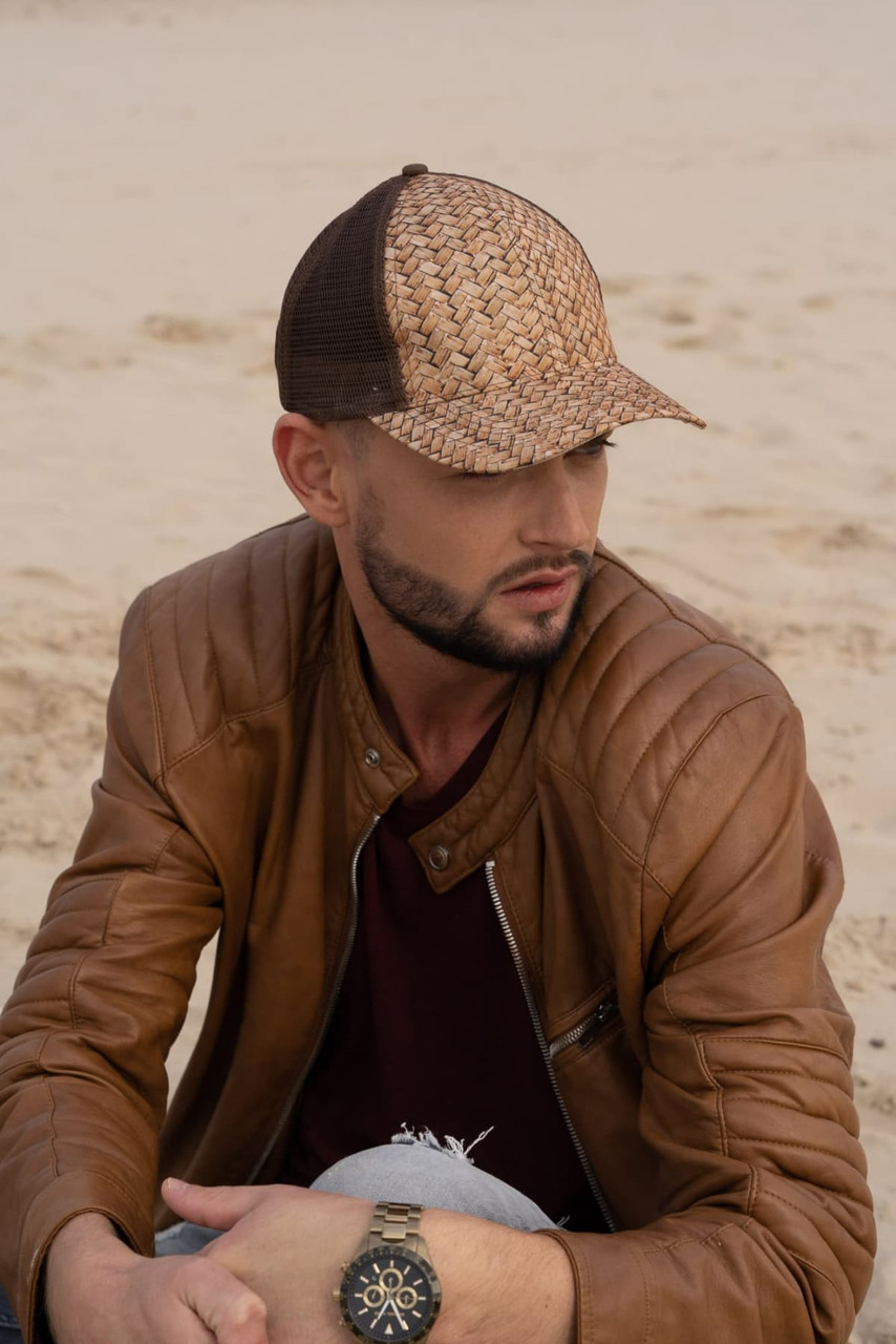 A stylish cap featuring a cane print design with a mesh back, worn by a man in a brown leather jacket.