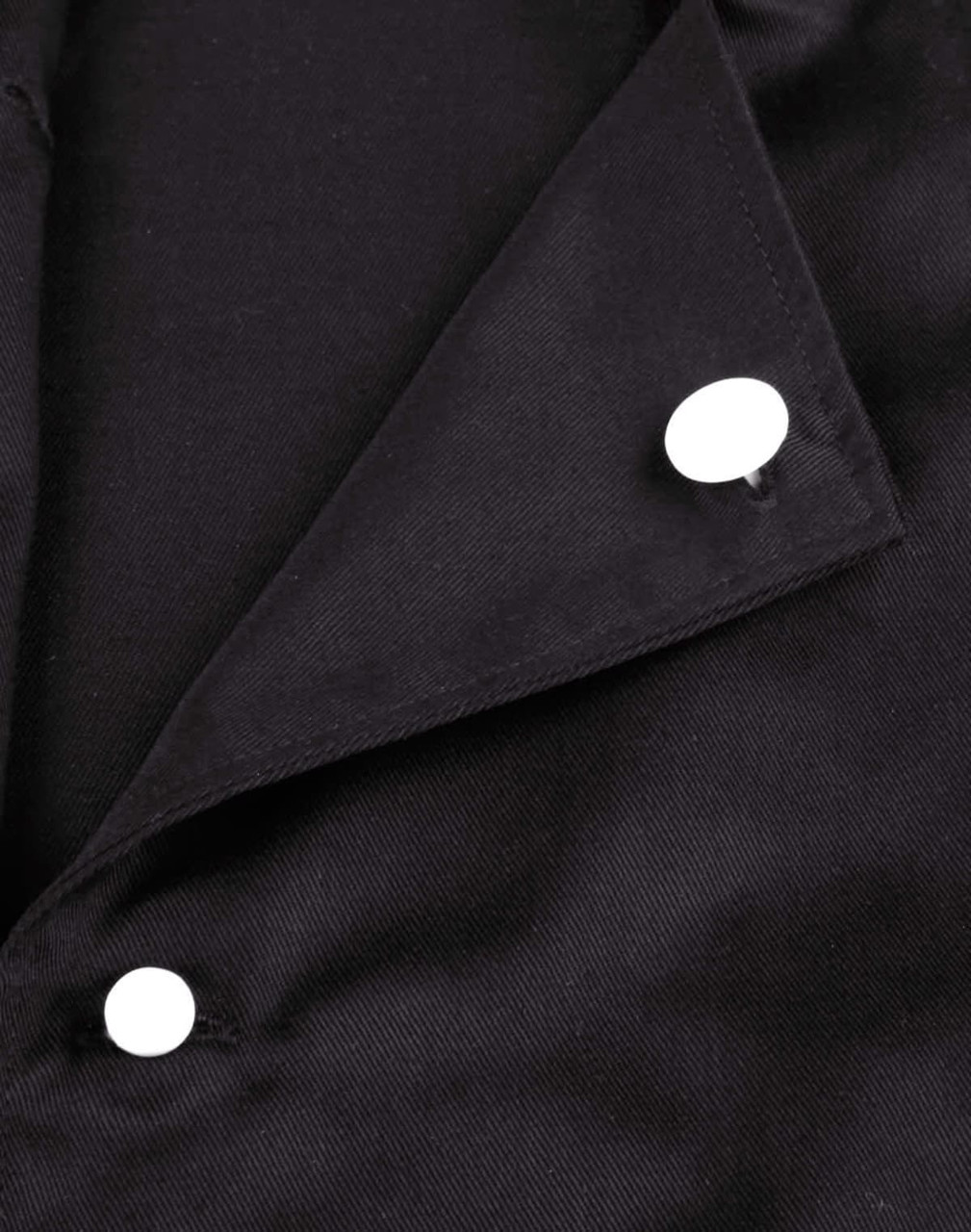 A close-up of a black chef jacket featuring two white exchangeable buttons on the collar.
