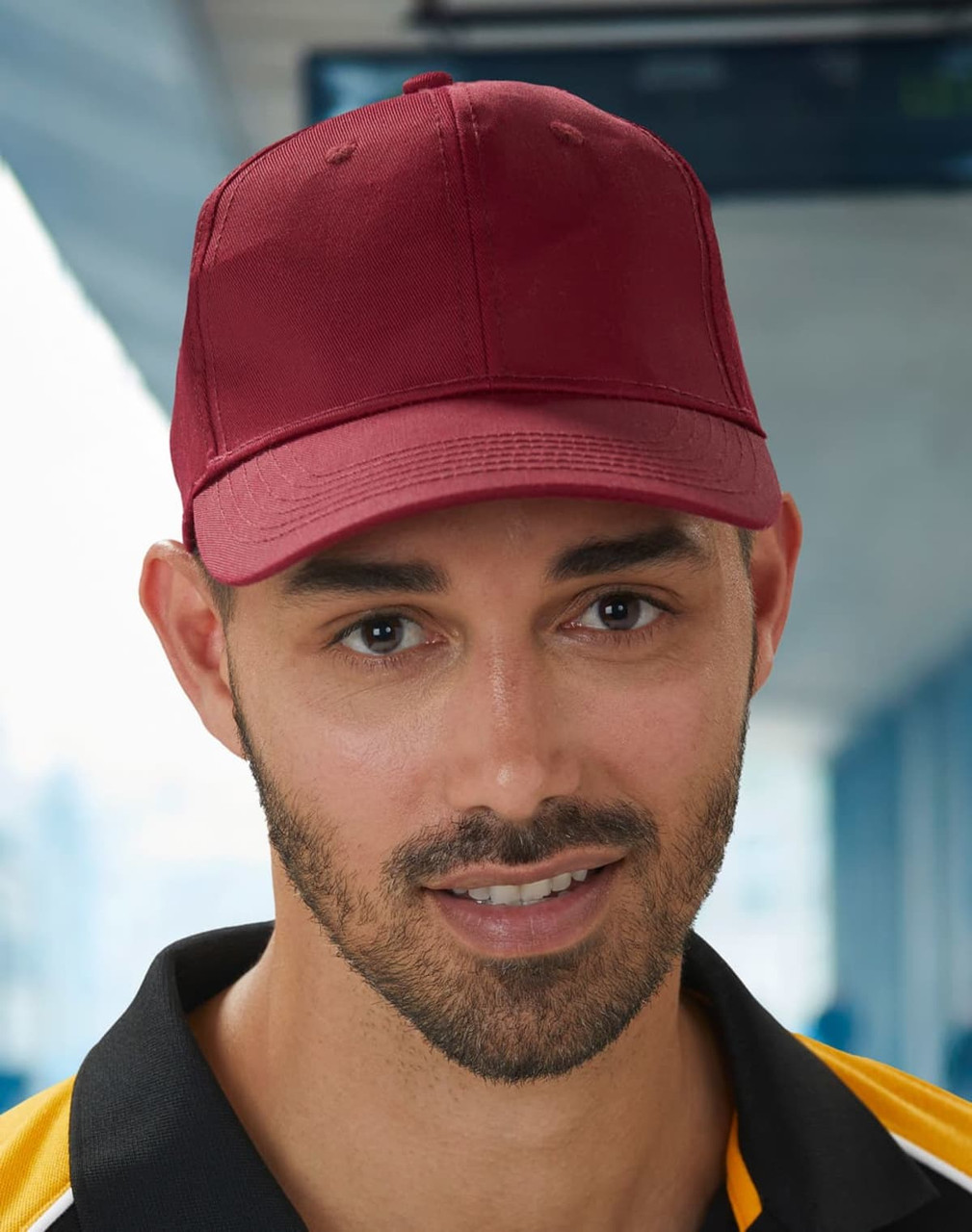 A red polycotton twill cap with a structured front and a curved peak, featuring a logo on the front.