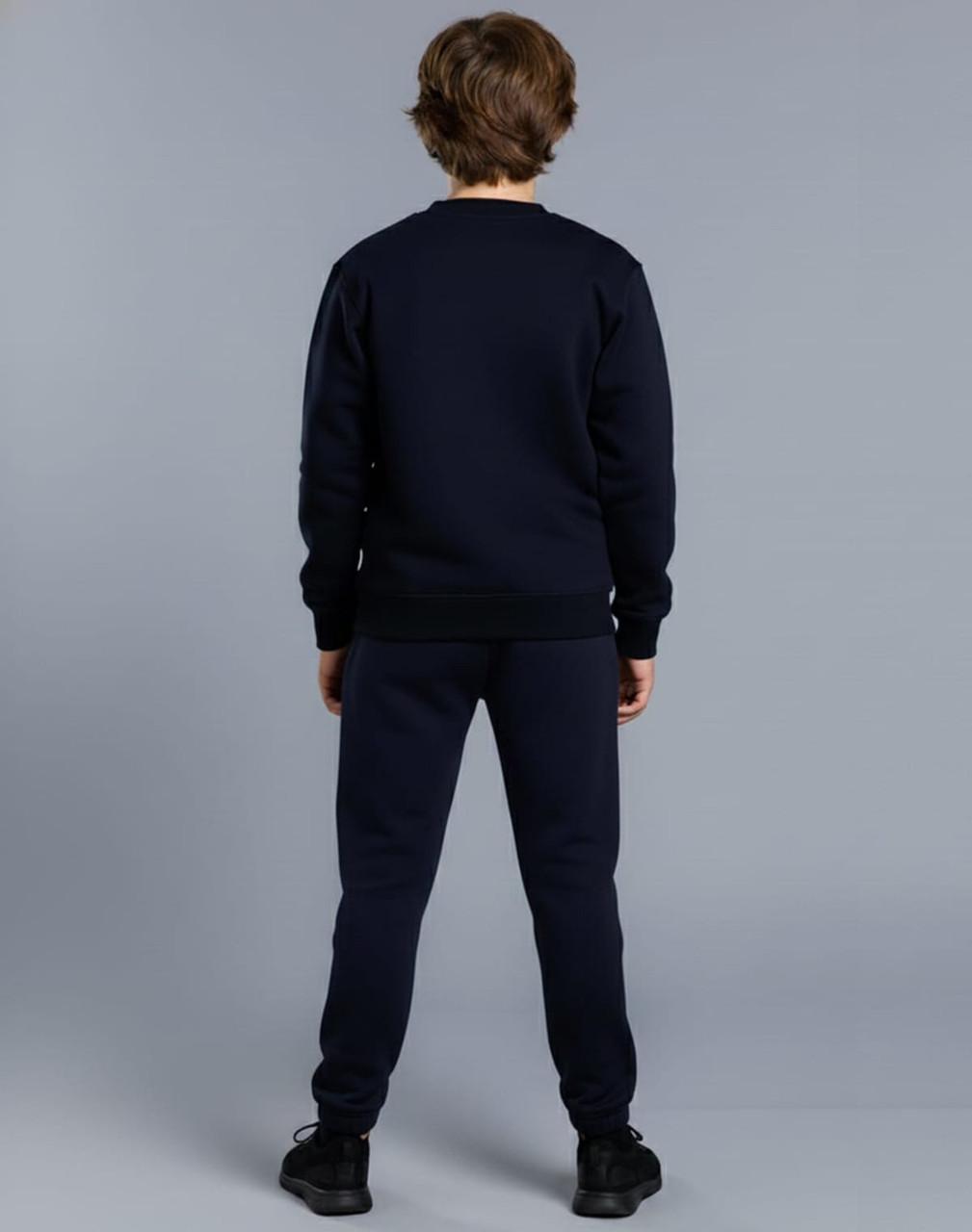 A navy fleecy sweater for kids, viewed from the back, paired with matching pants. The garment has a logo.