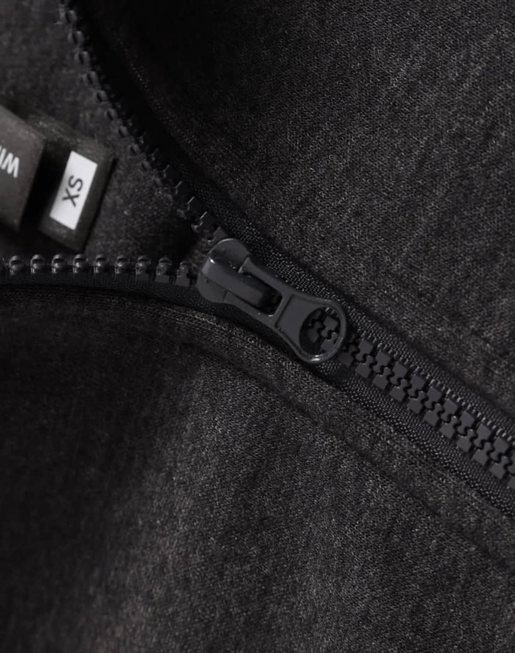 A close-up of a black half-zip collar fleecy jumper featuring a zipper and tags.
