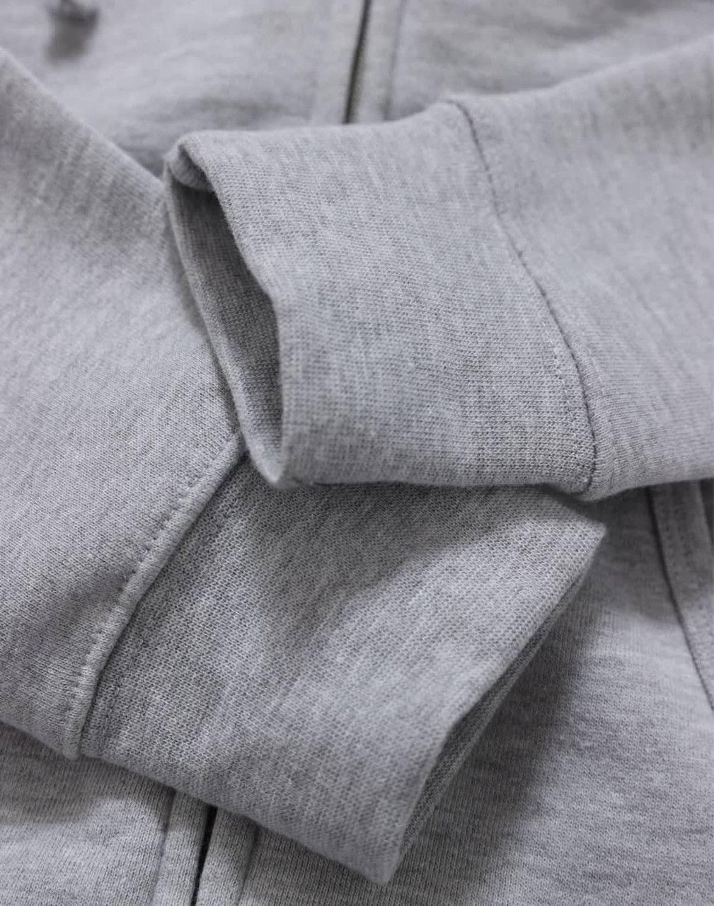 A close-up of a grey ladies' full-zip fleecy hoodie, featuring soft fabric and ribbed cuffs.