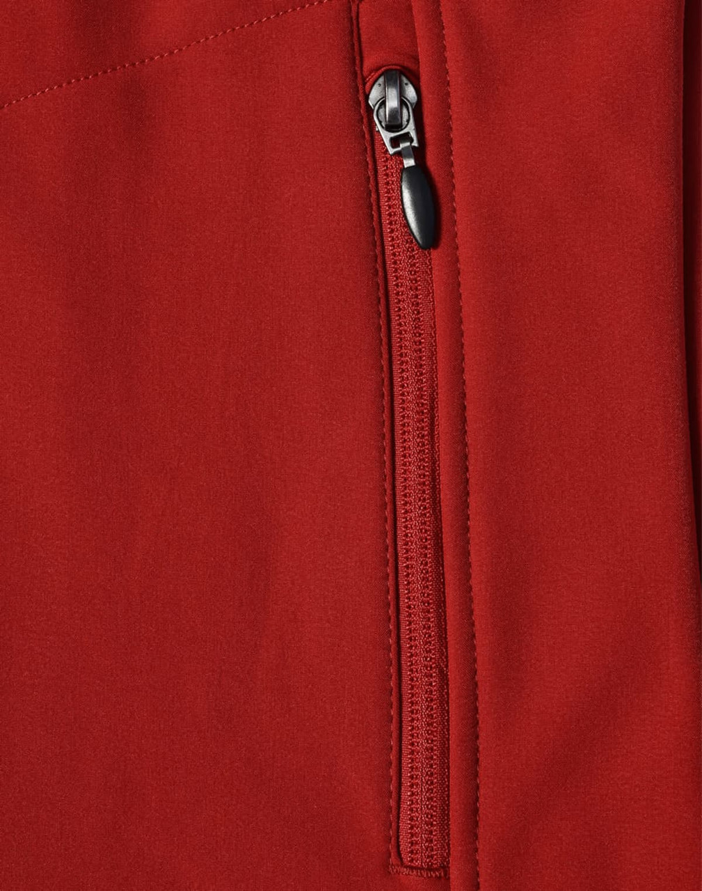 A close-up of a red softshell vest featuring a zippered pocket and a logo.