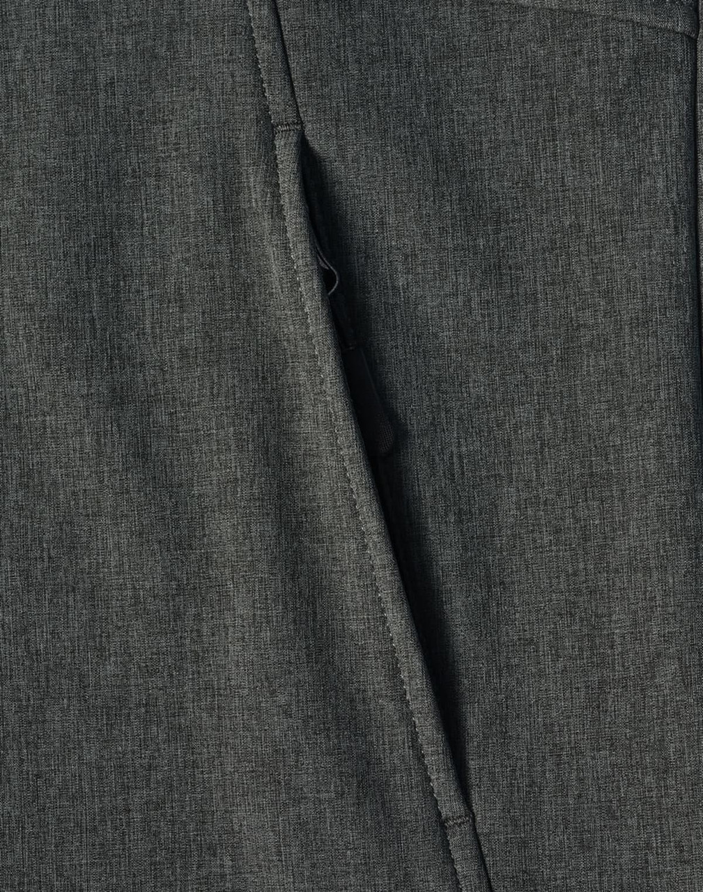 A close-up of a dark green softshell full zip hoodie featuring a zippered pocket and textured fabric.