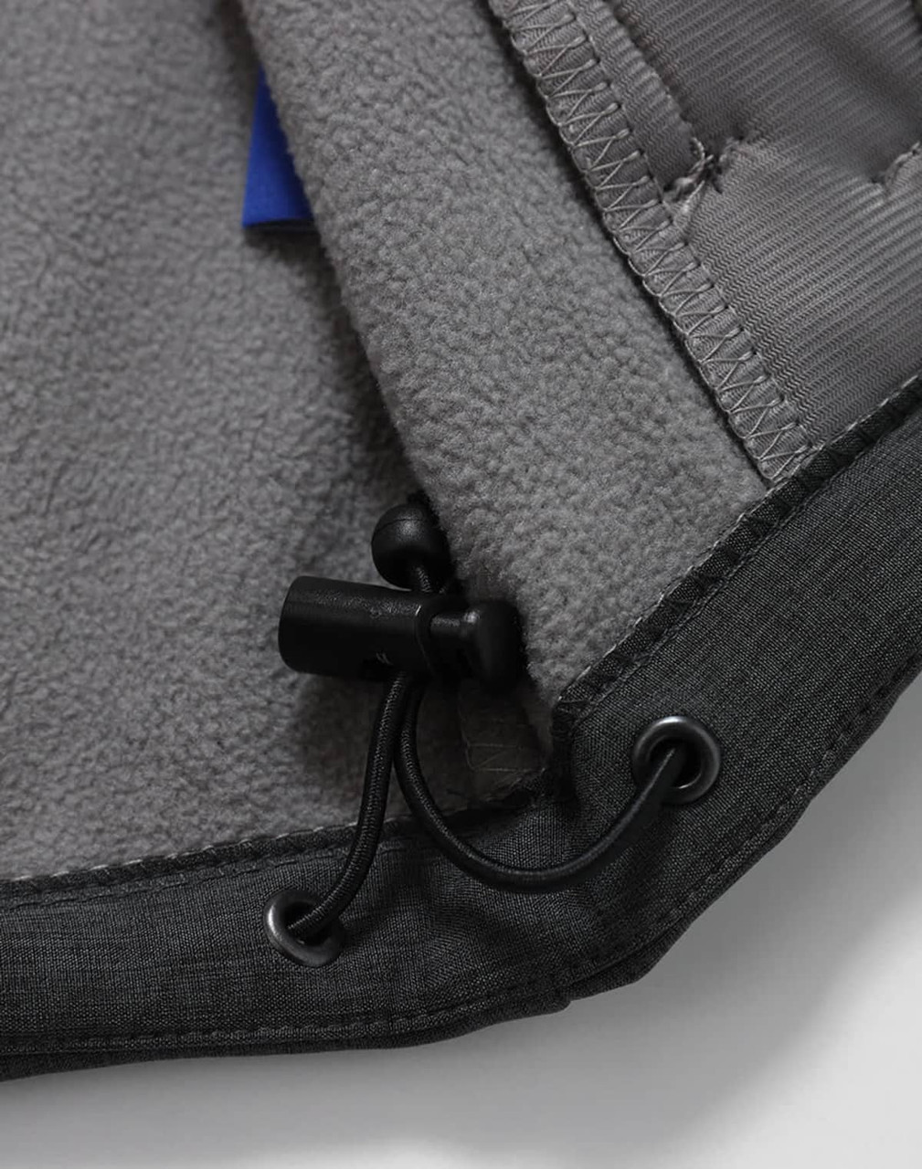 A close-up of the interior of a grey men's softshell full zip hoodie, featuring a drawstring and soft fabric lining.