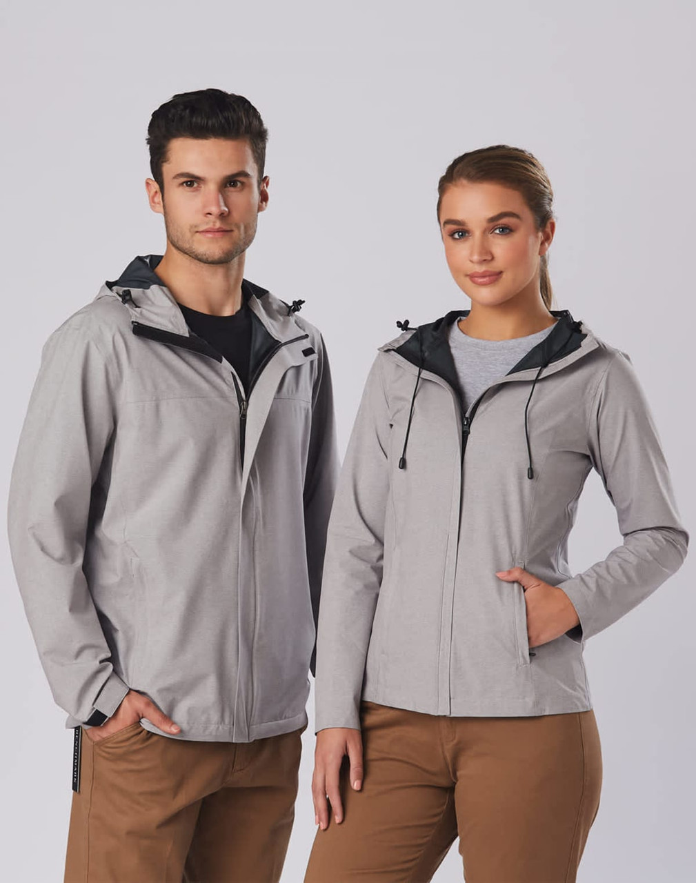 A grey men's waterproof performance jacket with a hood, featuring a logo, displayed on a male and female model.