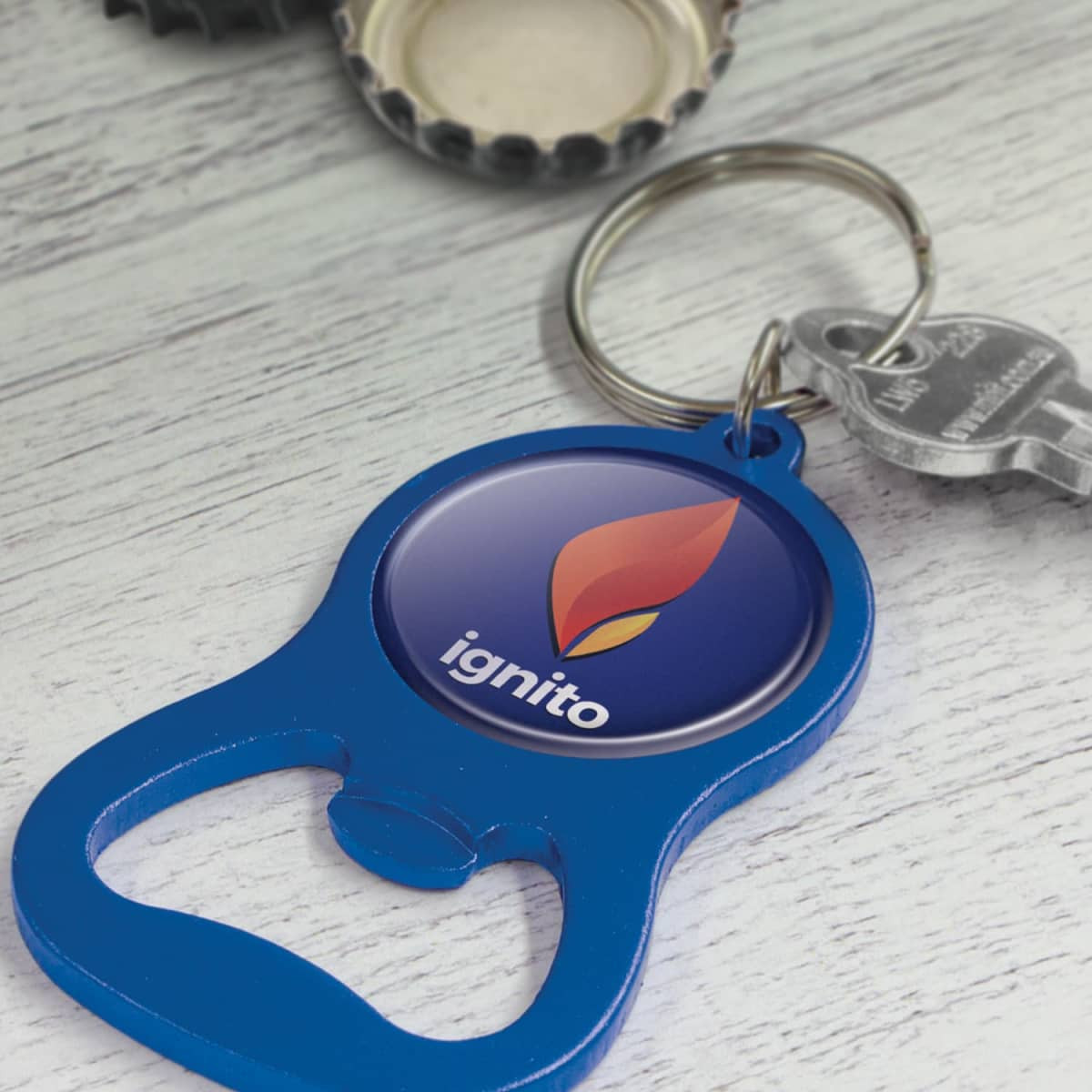 A blue bottle opener key ring with a round logo featuring a flame design and a metallic keychain attachment.