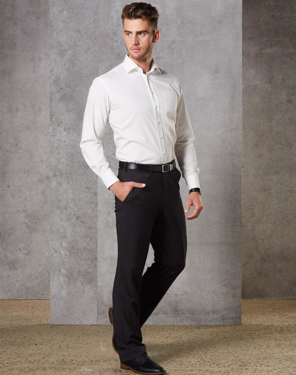 A man wearing black stretch wool blend pants paired with a white shirt and black shoes, standing in a modern setting.
