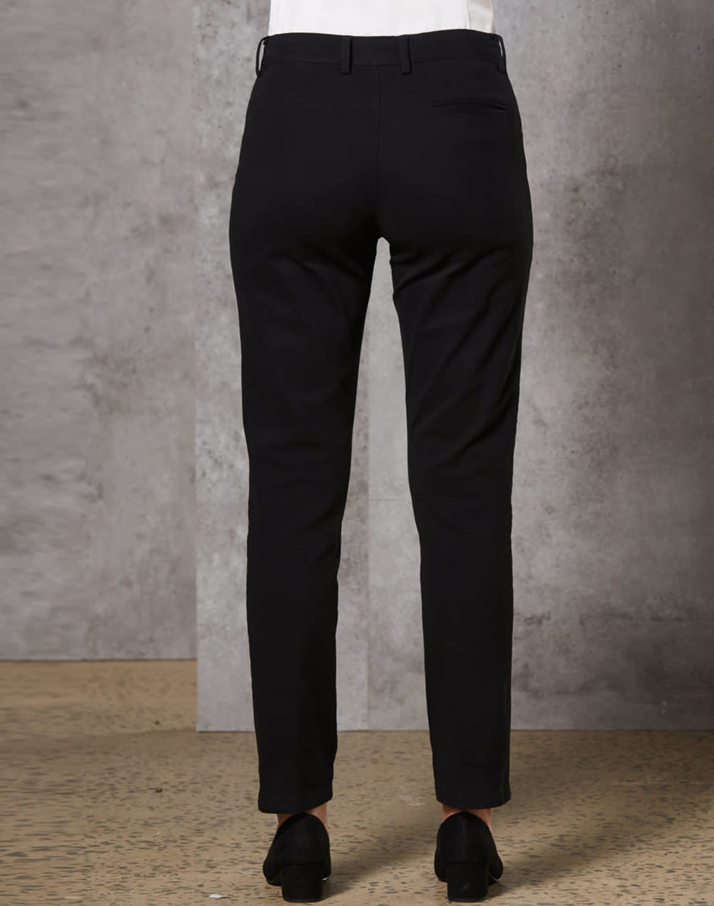 Black ladies' chino pants shown from the back, featuring a sleek fit and pockets. Includes a logo on the waistband.