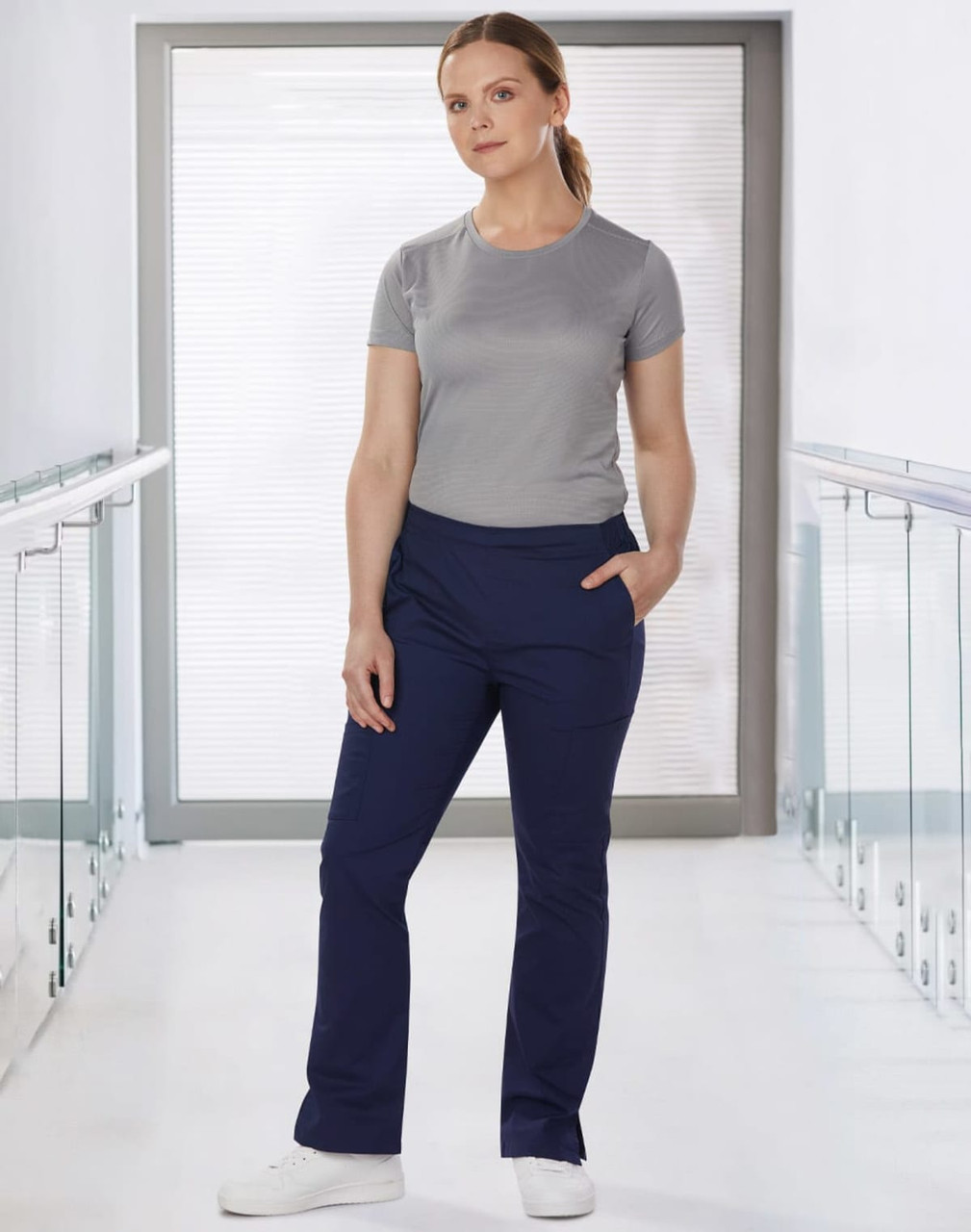 Ladies' solid colour scrub pants in navy, worn with a grey top, featuring a logo on the top.