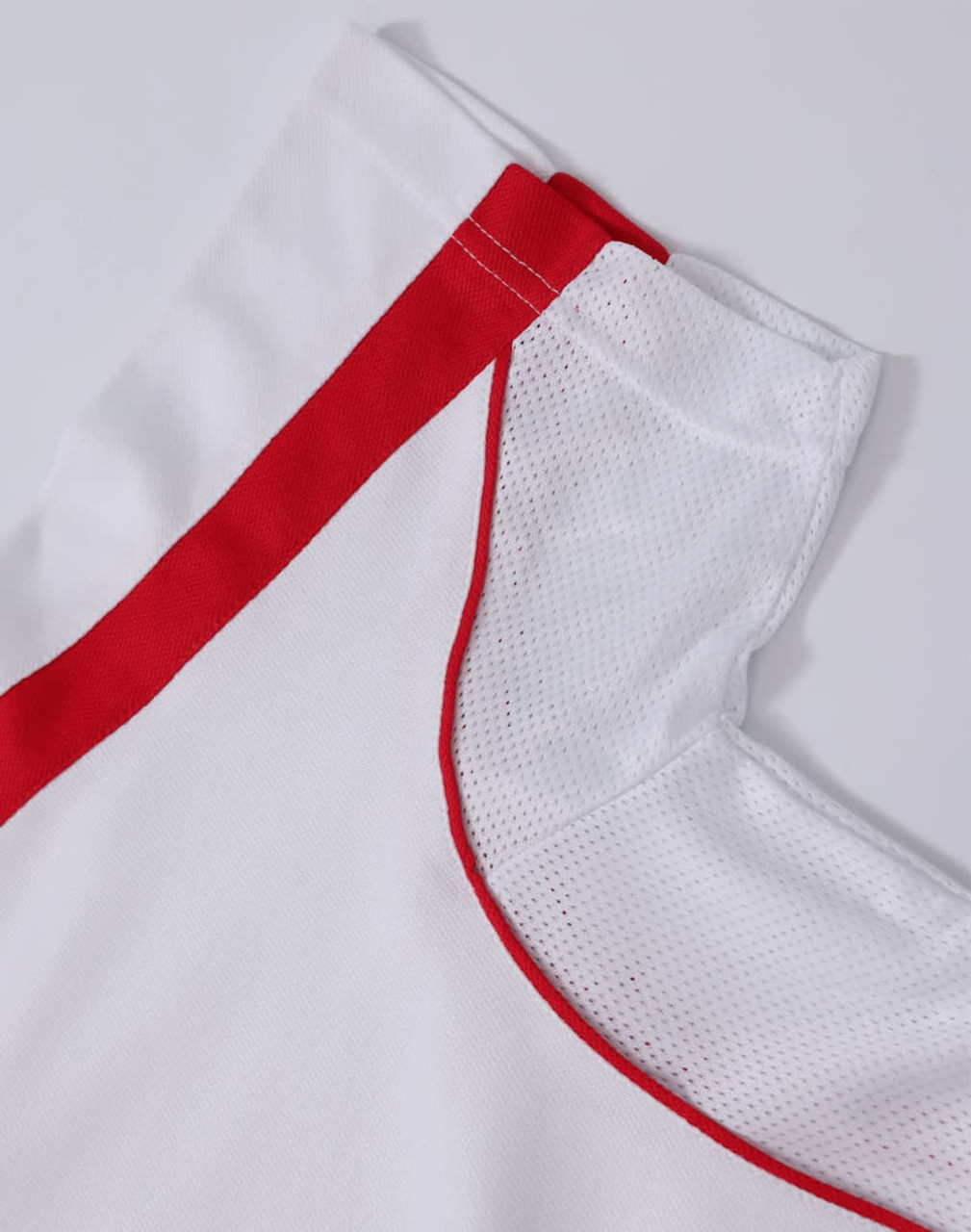 A white polo shirt with red trim, featuring a mesh detail along the collar and shoulder. It has a logo present.