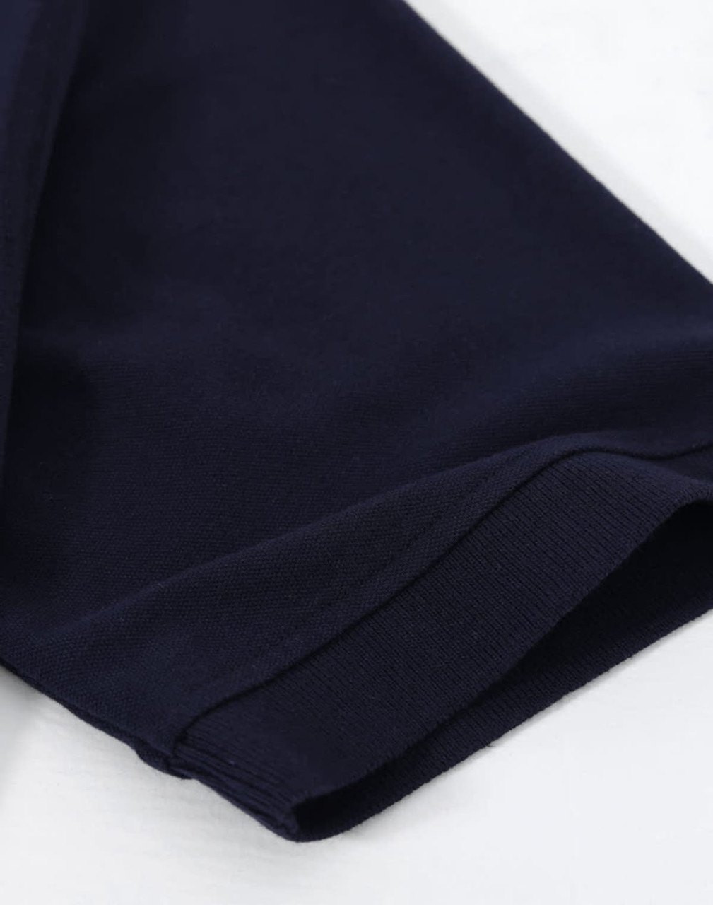 A navy cotton stretch polo shirt, displaying the sleeve cuff and fabric texture, with a branding logo.