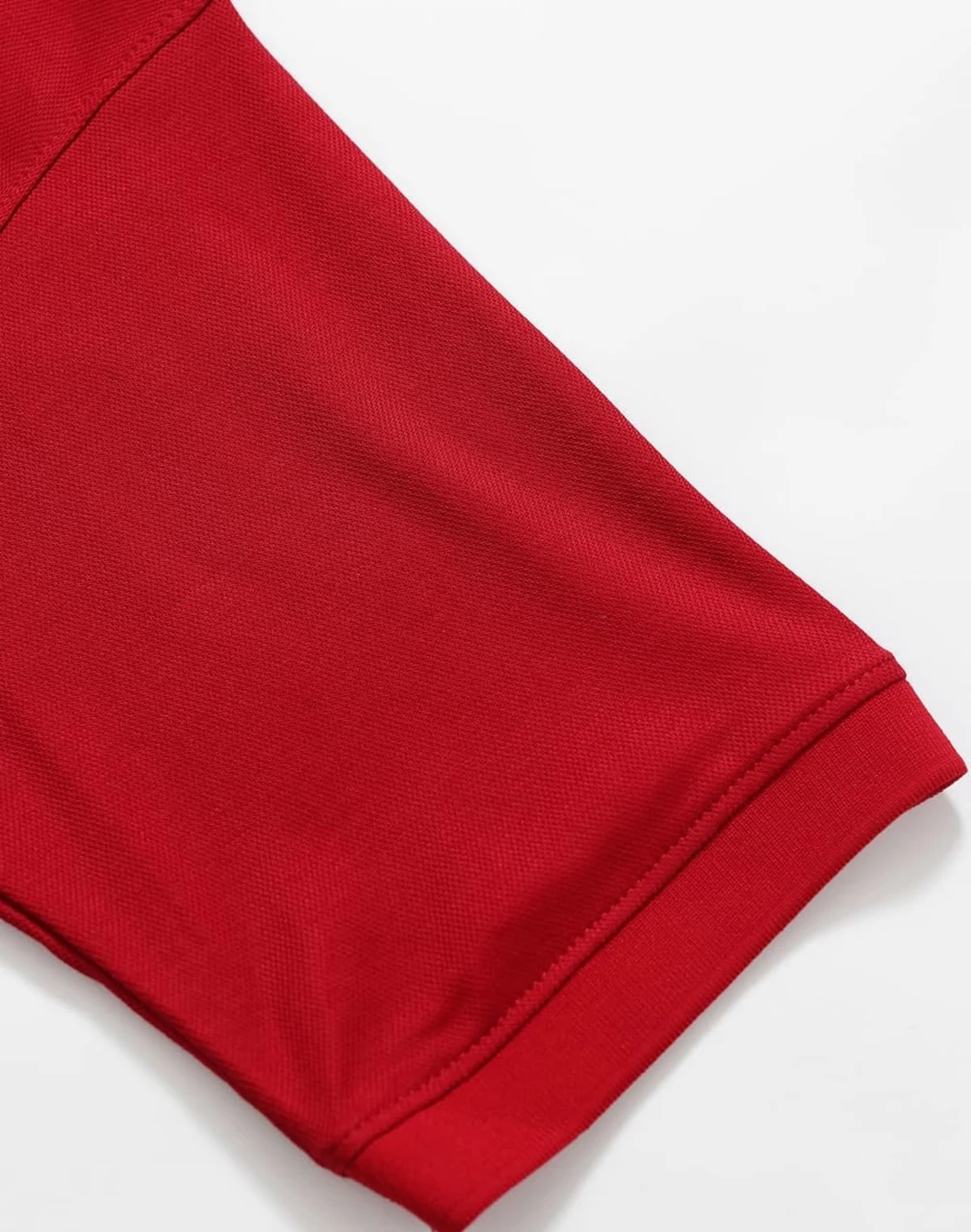A close-up of a red polo shirt sleeve featuring a smooth fabric texture and a neatly finished hem.