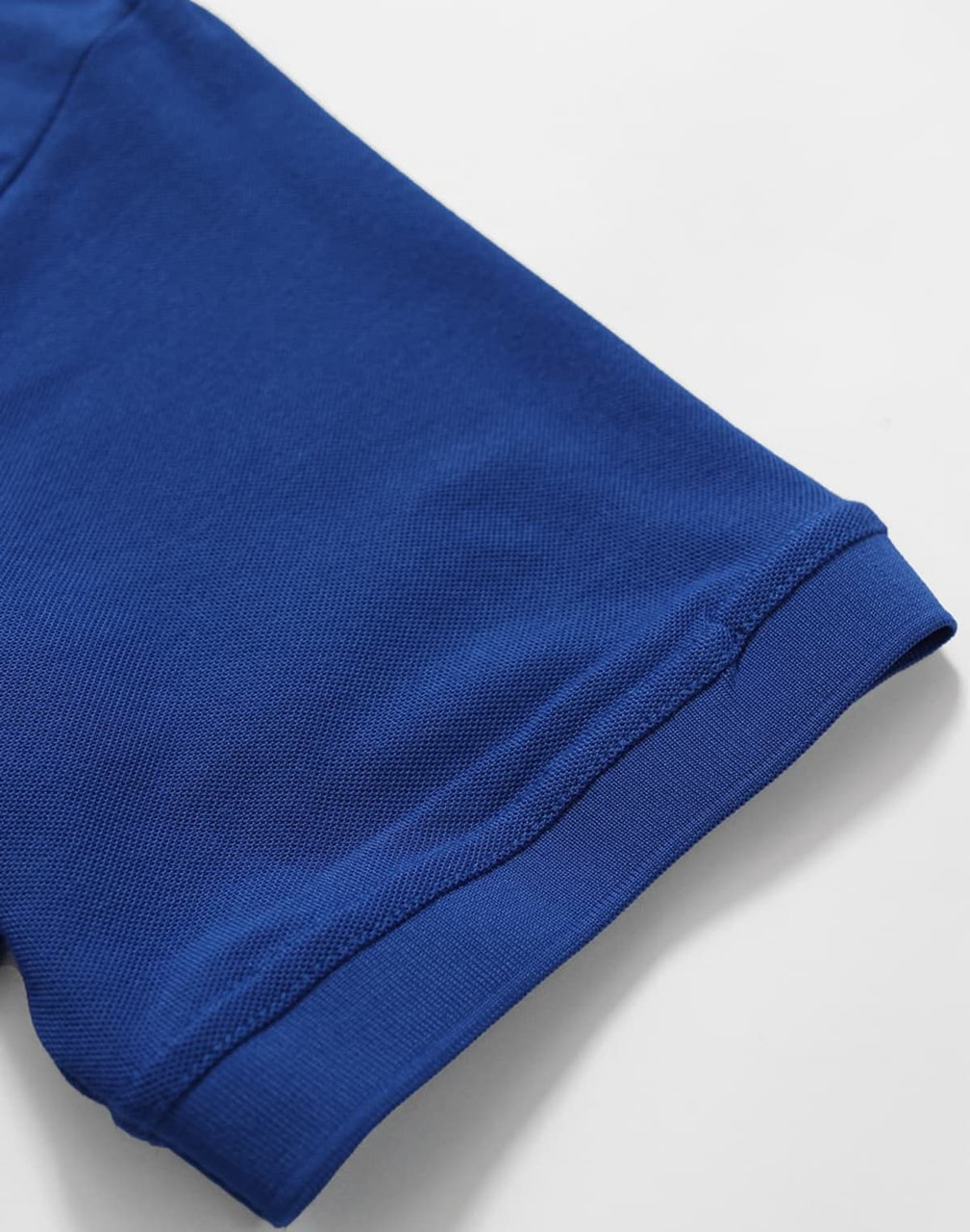 A close-up of a blue polo shirt sleeve featuring a smooth hem and textured fabric. The shirt has a logo on it.