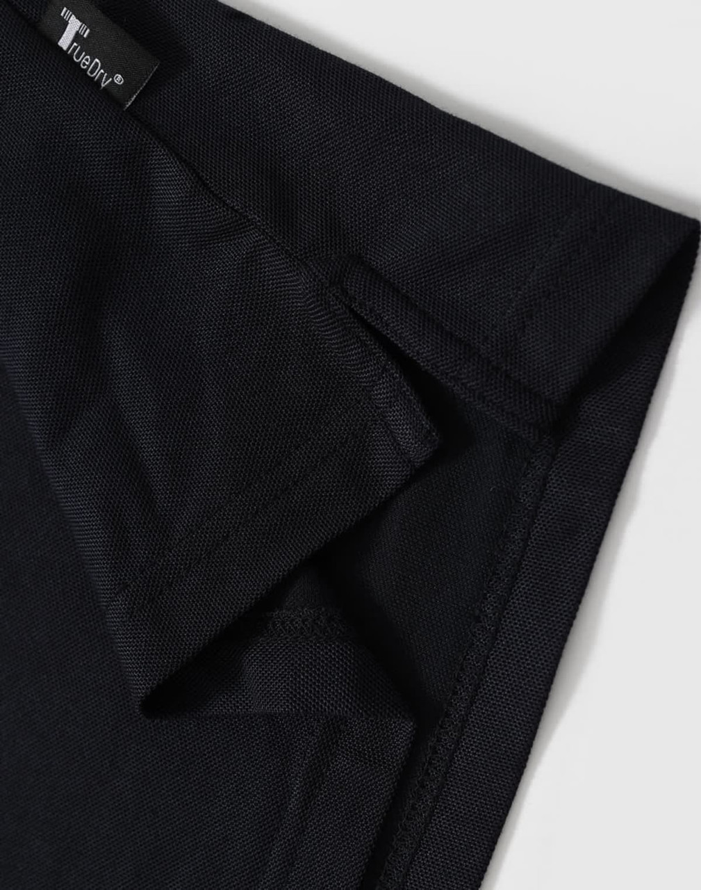A black polo shirt with a short collar and branded tag detailing at the neckline.