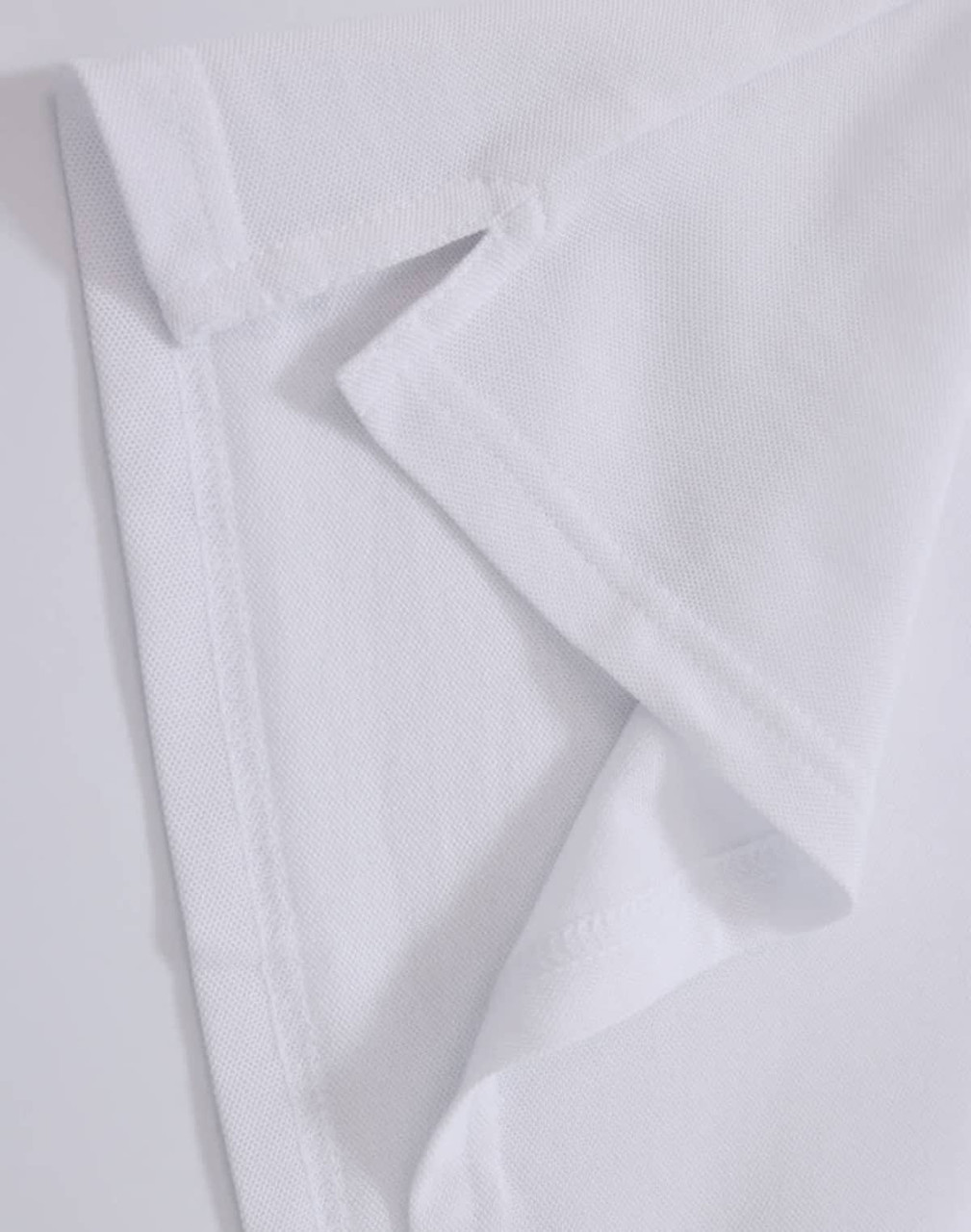 A close-up of a white polo shirt fabric, showcasing the collar and stitching details. Contains a logo.