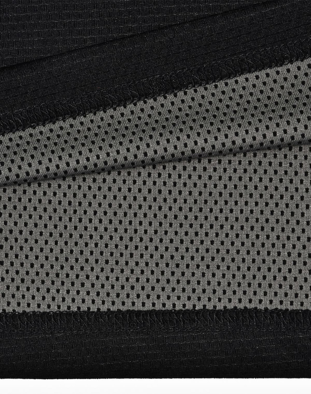 A close-up of black and grey fabric, featuring a textured surface and mesh pattern, ideal for polo shirts.