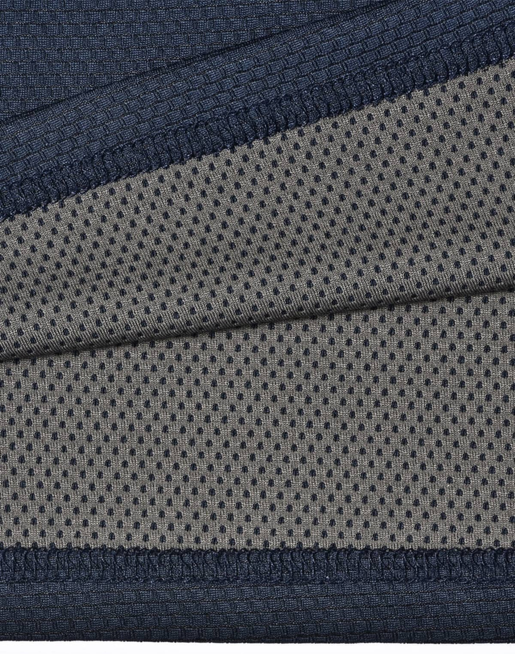 A close-up of a two-tone polo shirt featuring a navy blue top section and a grey, dotted underlay. The fabric is textured and breathable.