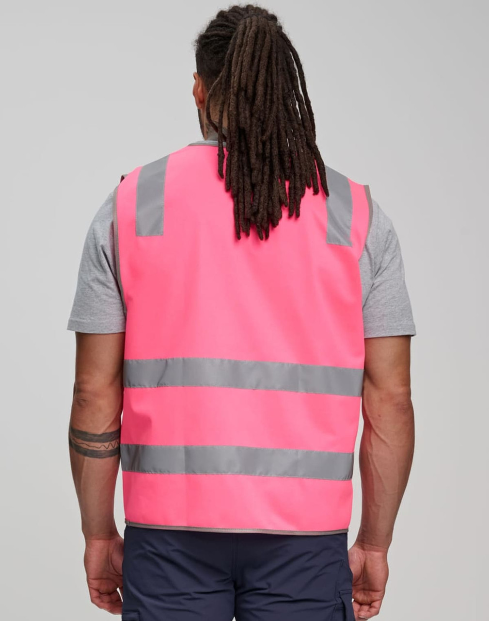 A pink safety vest featuring shoulder reflective tapes and grey stripes, worn by a person from behind.