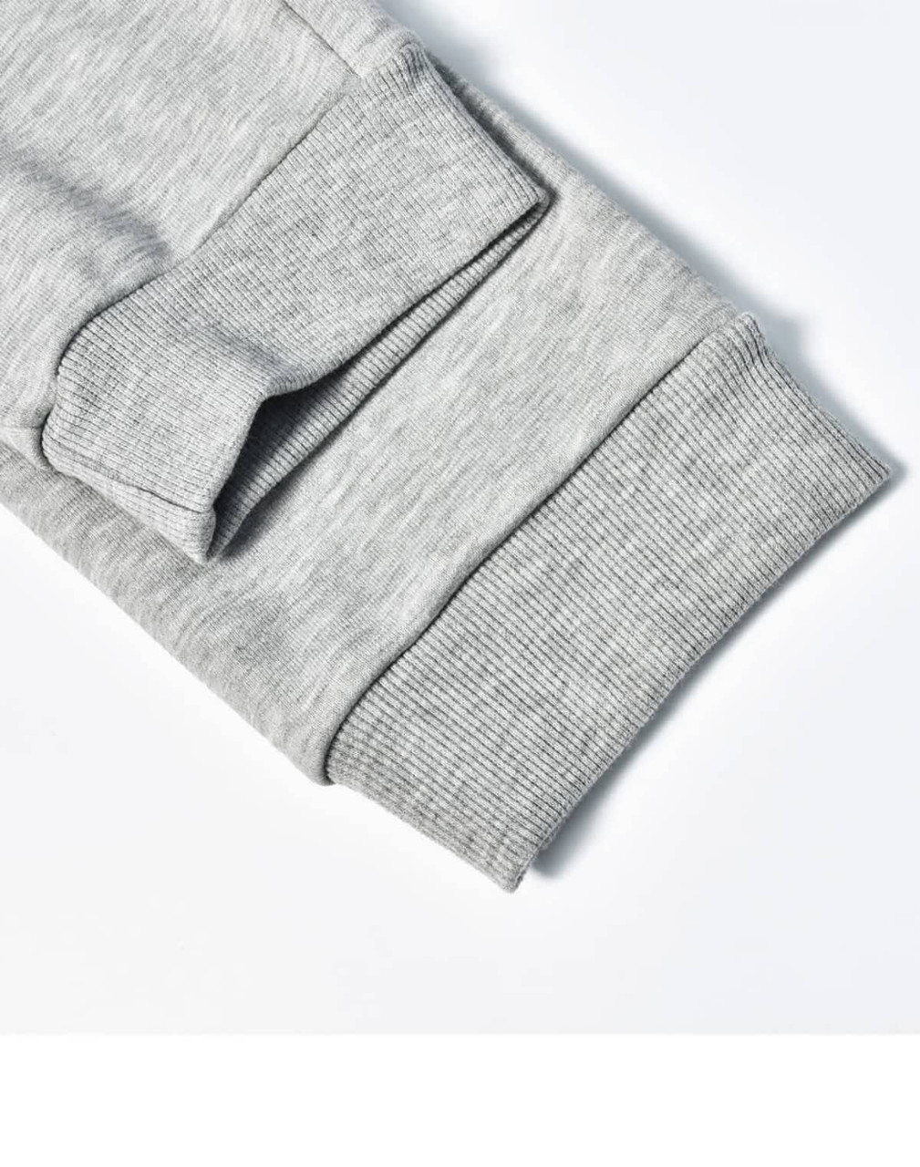 A close-up of grey poly/cotton terry sweat pant cuffs featuring ribbed texture and stitching details.