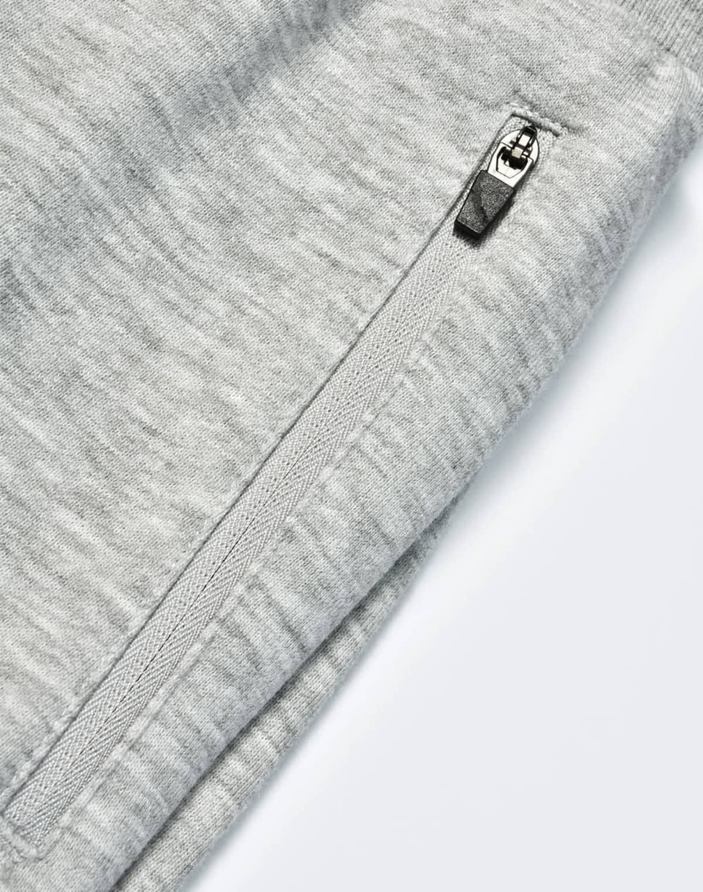 A close-up of grey kids' poly/cotton terry sweat pants featuring a zip pocket and soft fabric texture.