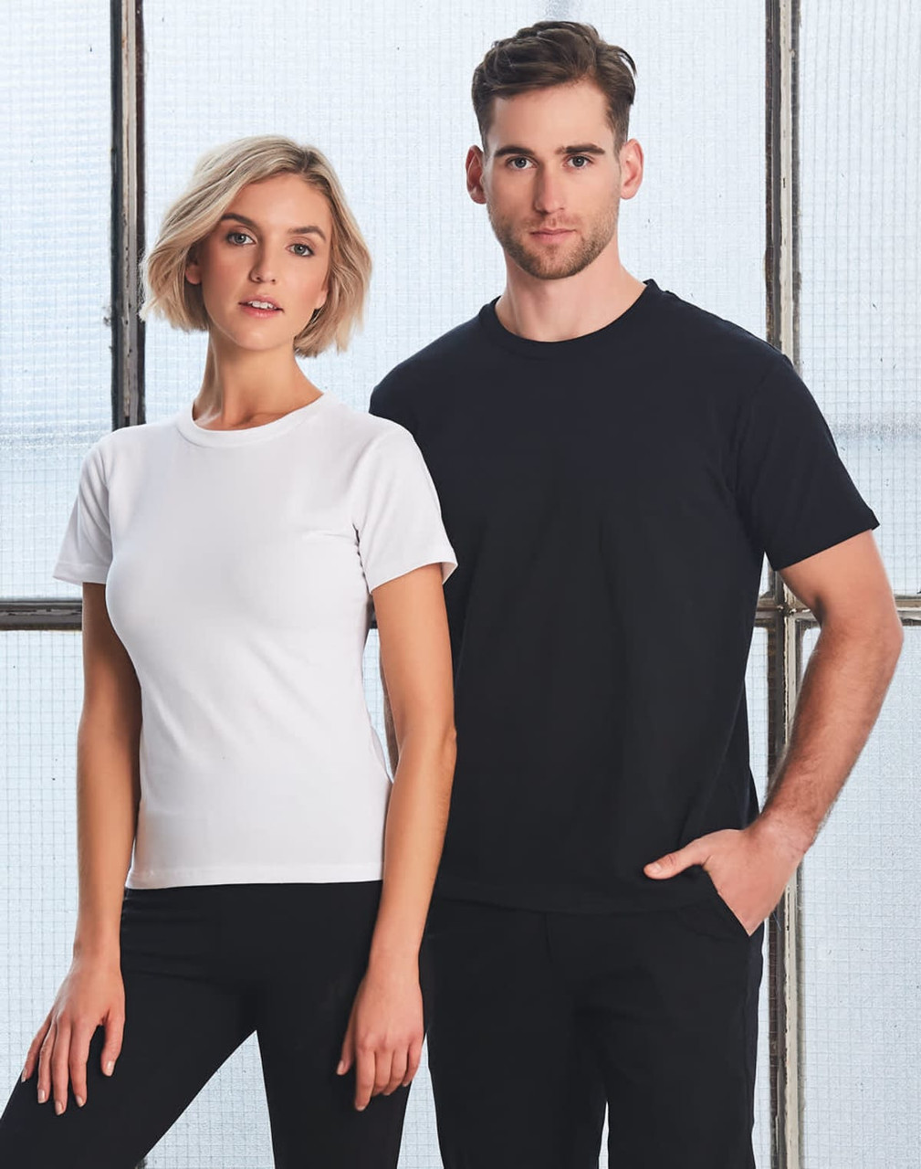 A fitted white women's t-shirt and a black men's t-shirt, both made of stretch fabric. Each shirt has a logo.
