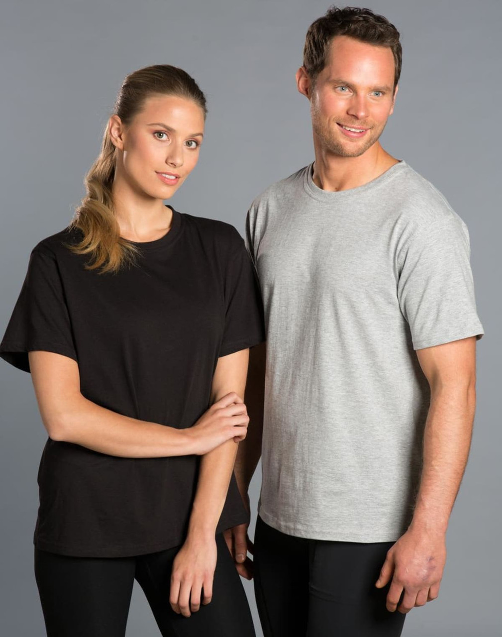 A black unisex cotton tee and a grey unisex cotton tee are worn by a man and a woman. Both tees feature a logo.